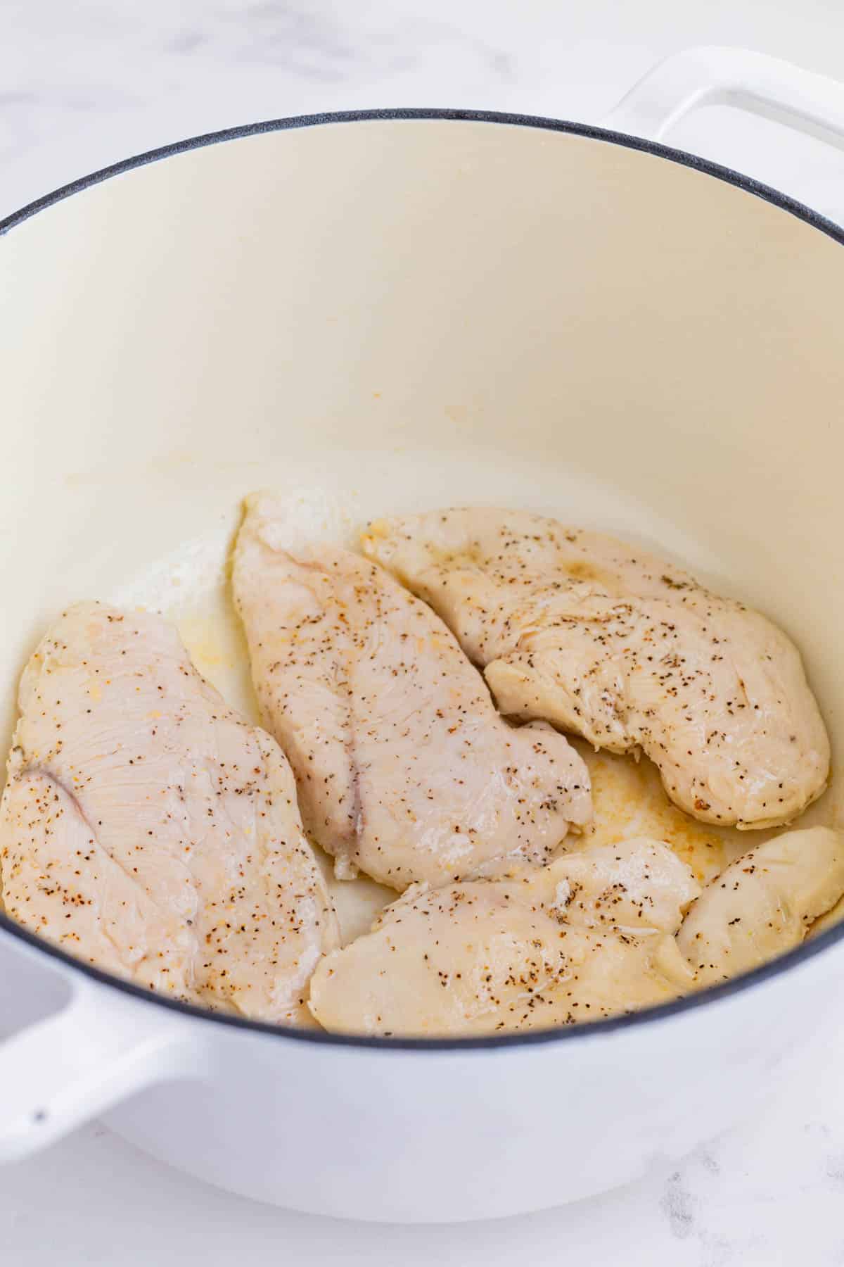 Prepared chicken is cooked in oil in a skillet.