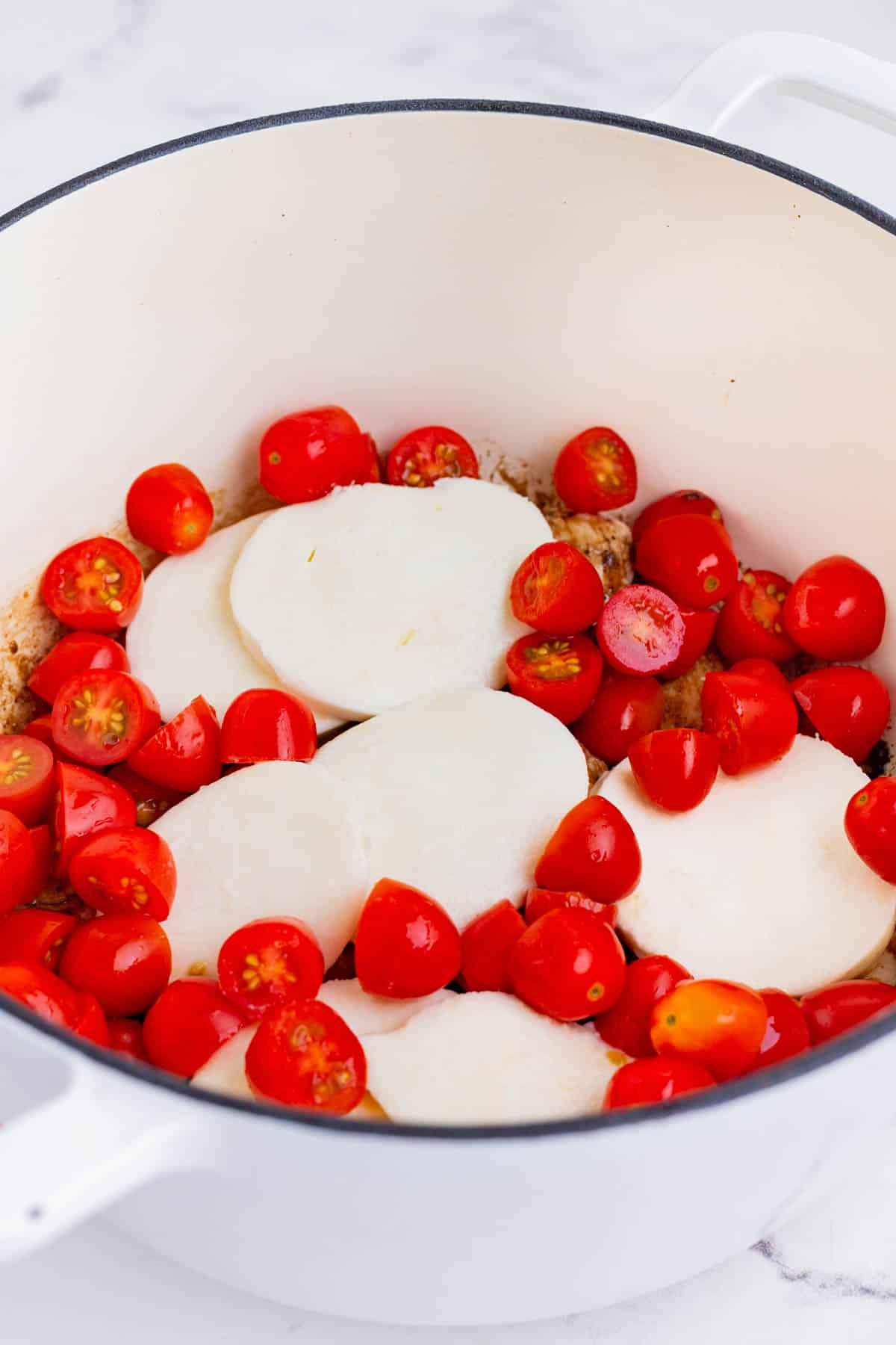 Mozzarella cheese and tomatoes are piled on top of the chicken.