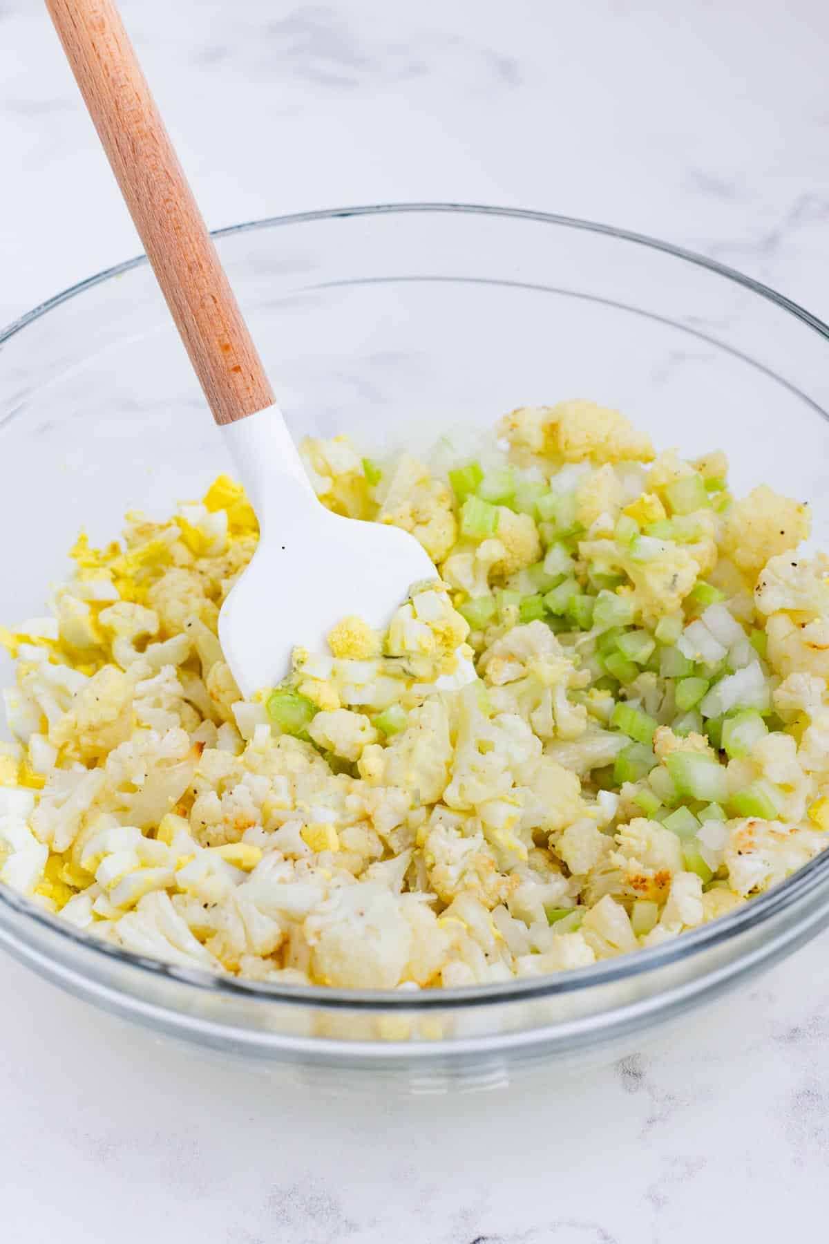 Roasted cauliflower, eggs, celery, onion, and sauce are mixed together.