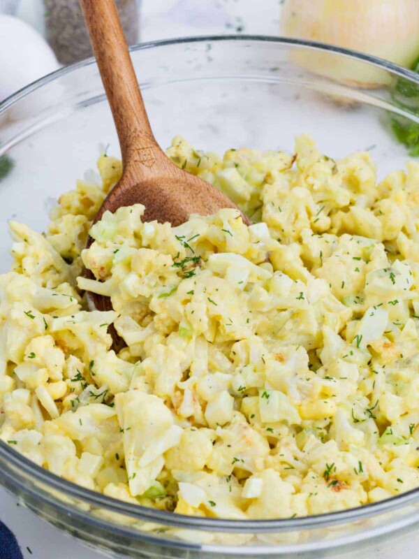 A wooden spoon is used to serve cauliflower potato salad.