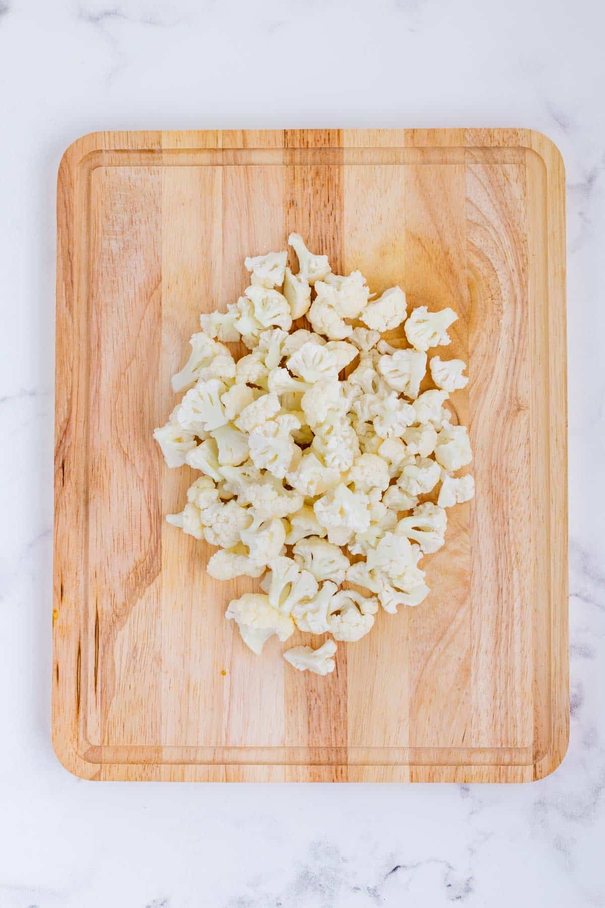 Chopped cauliflower is on a cutting board.