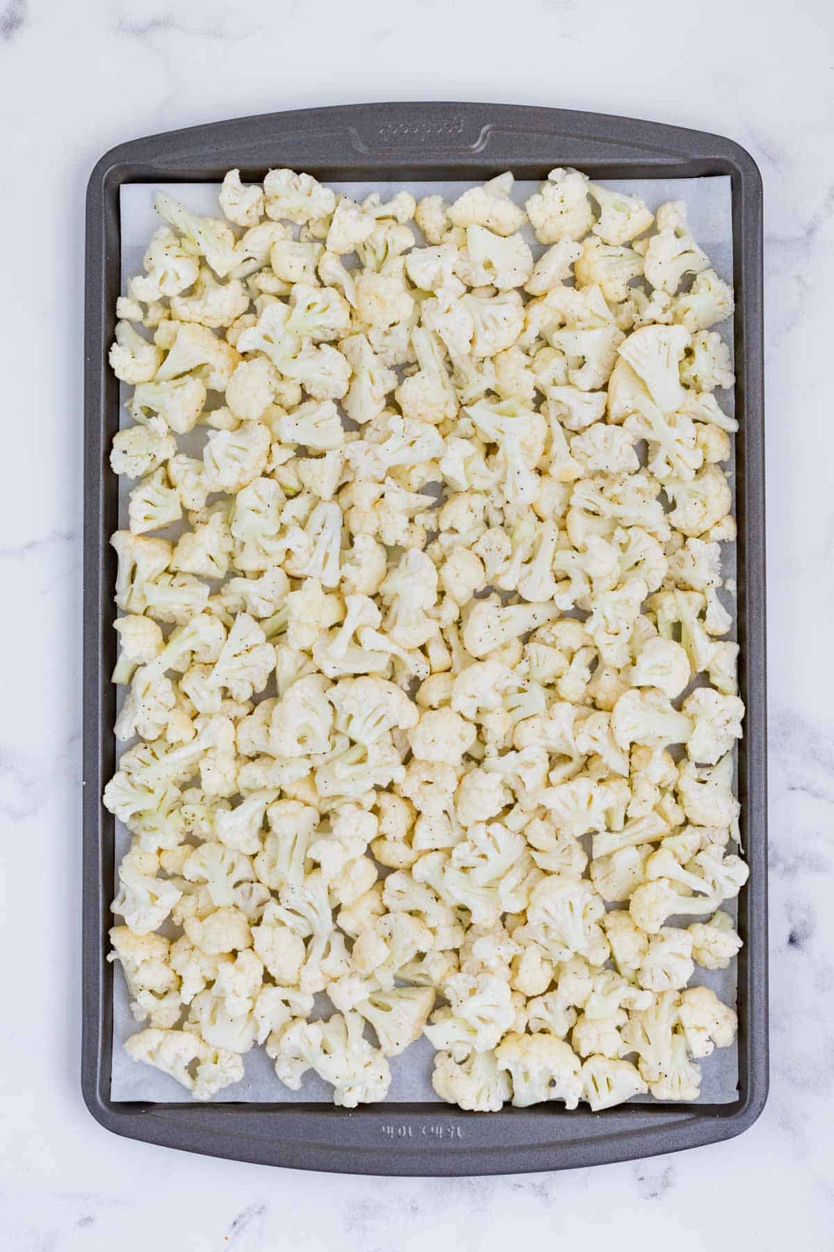 Seasoned cauliflower is roasted on a baking sheet.