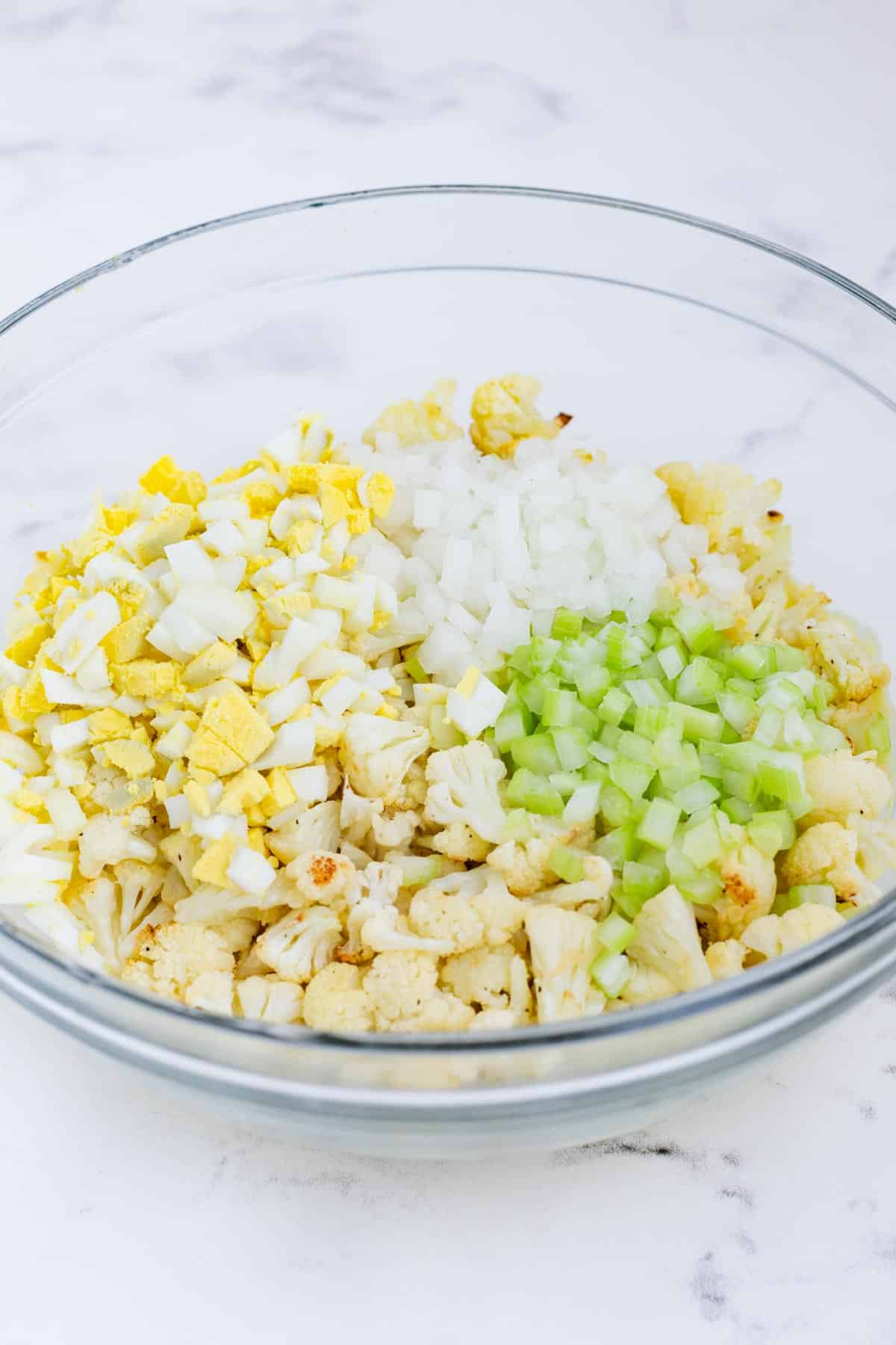 Roasted cauliflower, eggs, celery, onion, and sauce are mixed together.