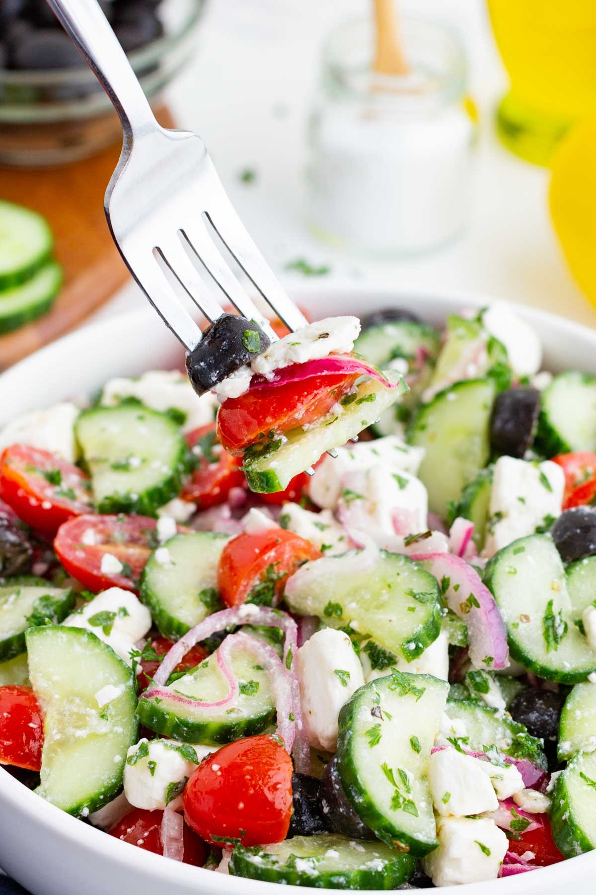 A fork digs into a bowl full of Greek cucumber salad.