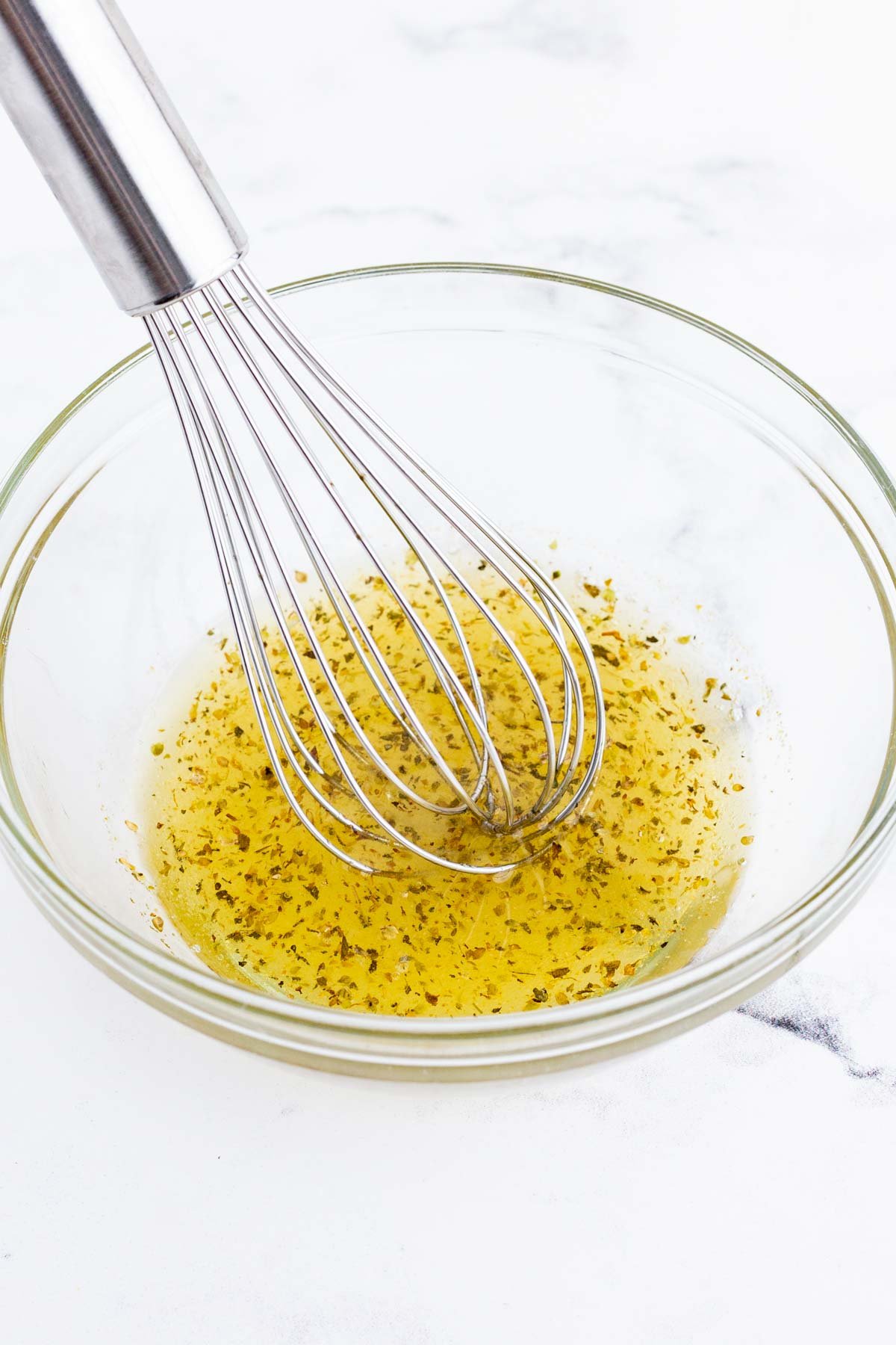 A Greek dressing is whisked in a bowl.