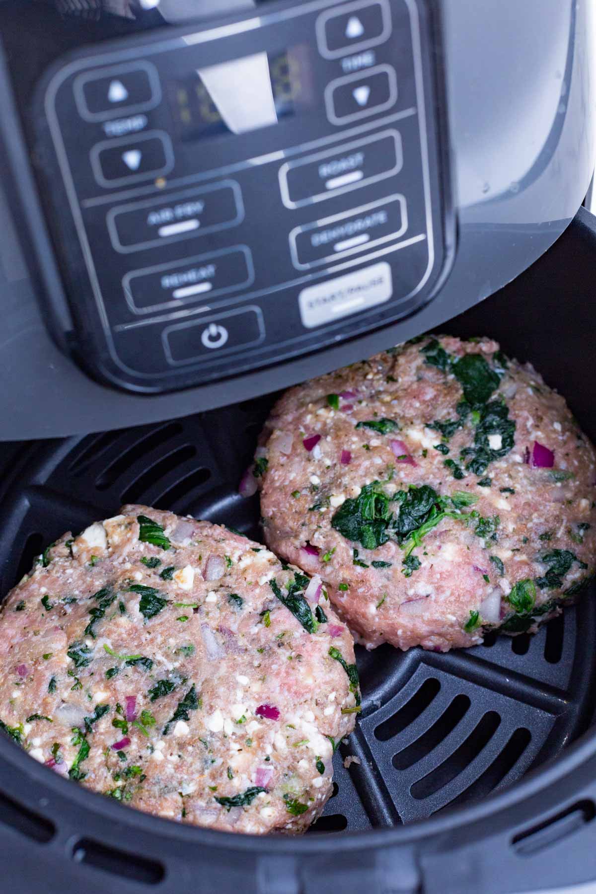 Burger patties are placed in an air fryer.