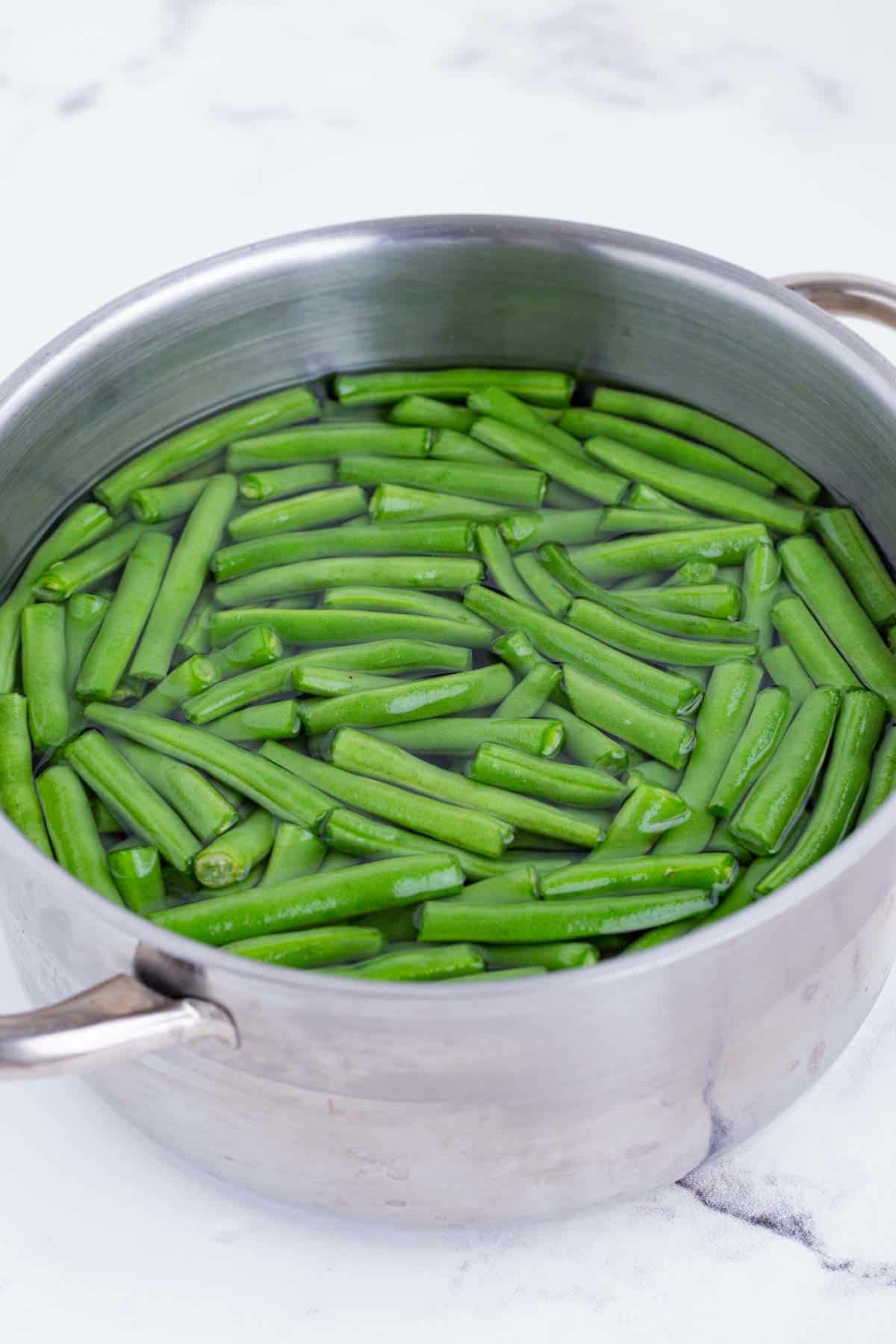Green beans are blanched in a pot.