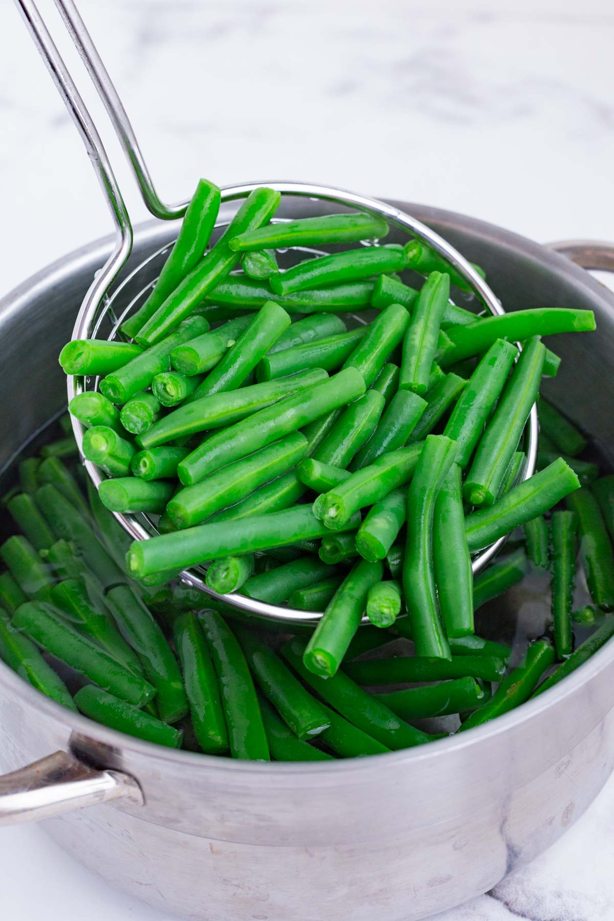 A slotted spoon removes the green beans