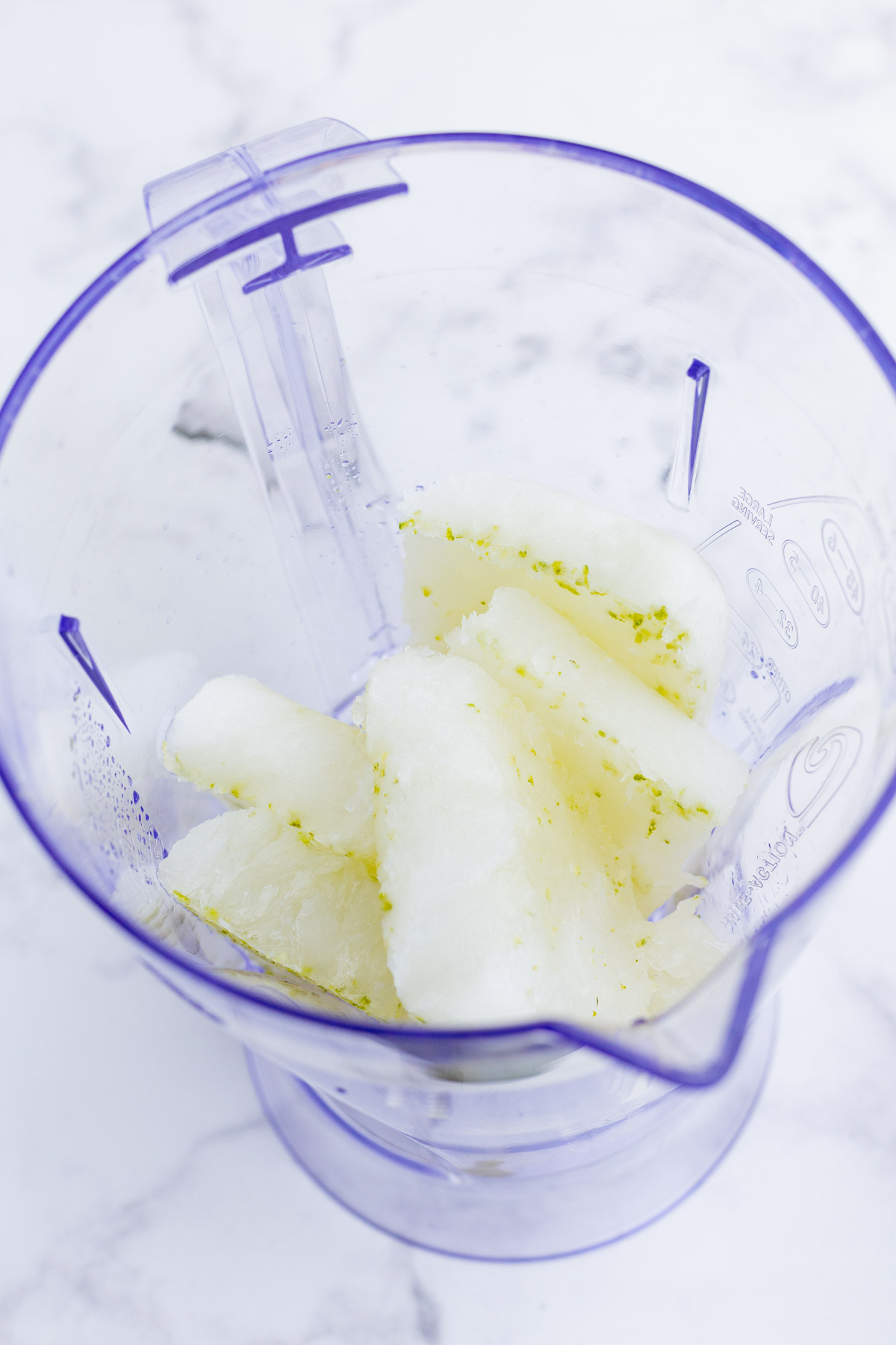 Semi-frozen lime sorbet is added to a blender.