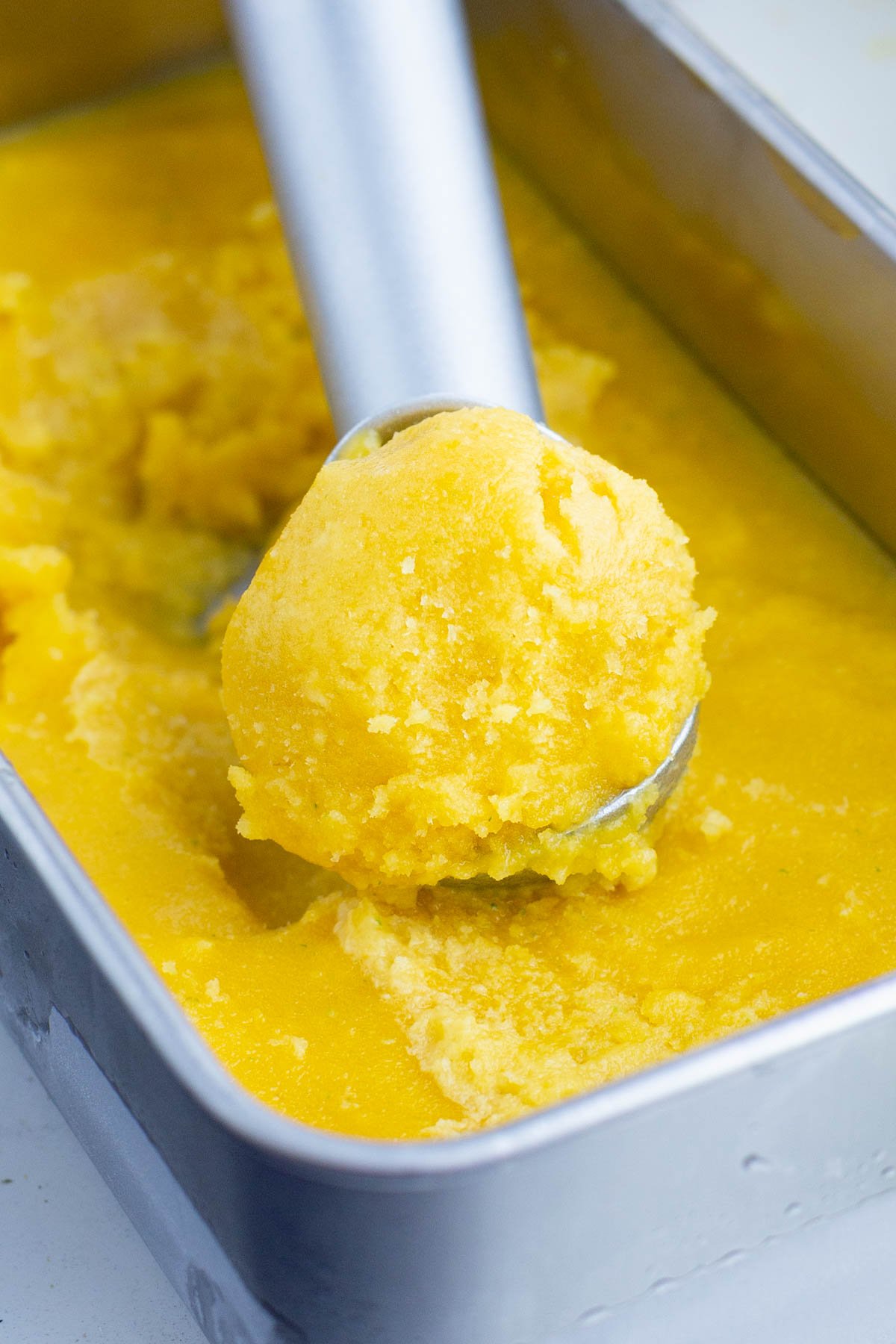 An ice cream scoop serves up some mango sorbet.