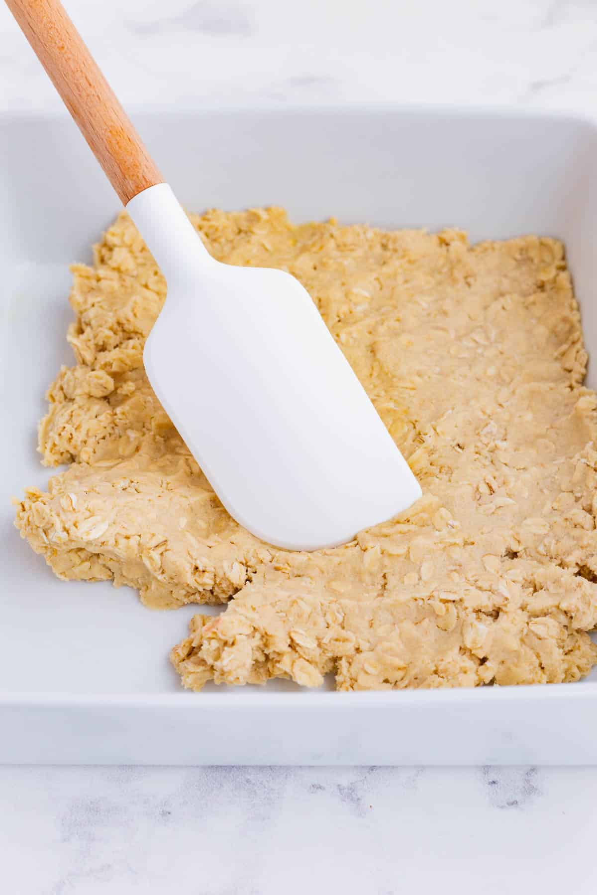Shortbread dough is pressed into a baking dish.