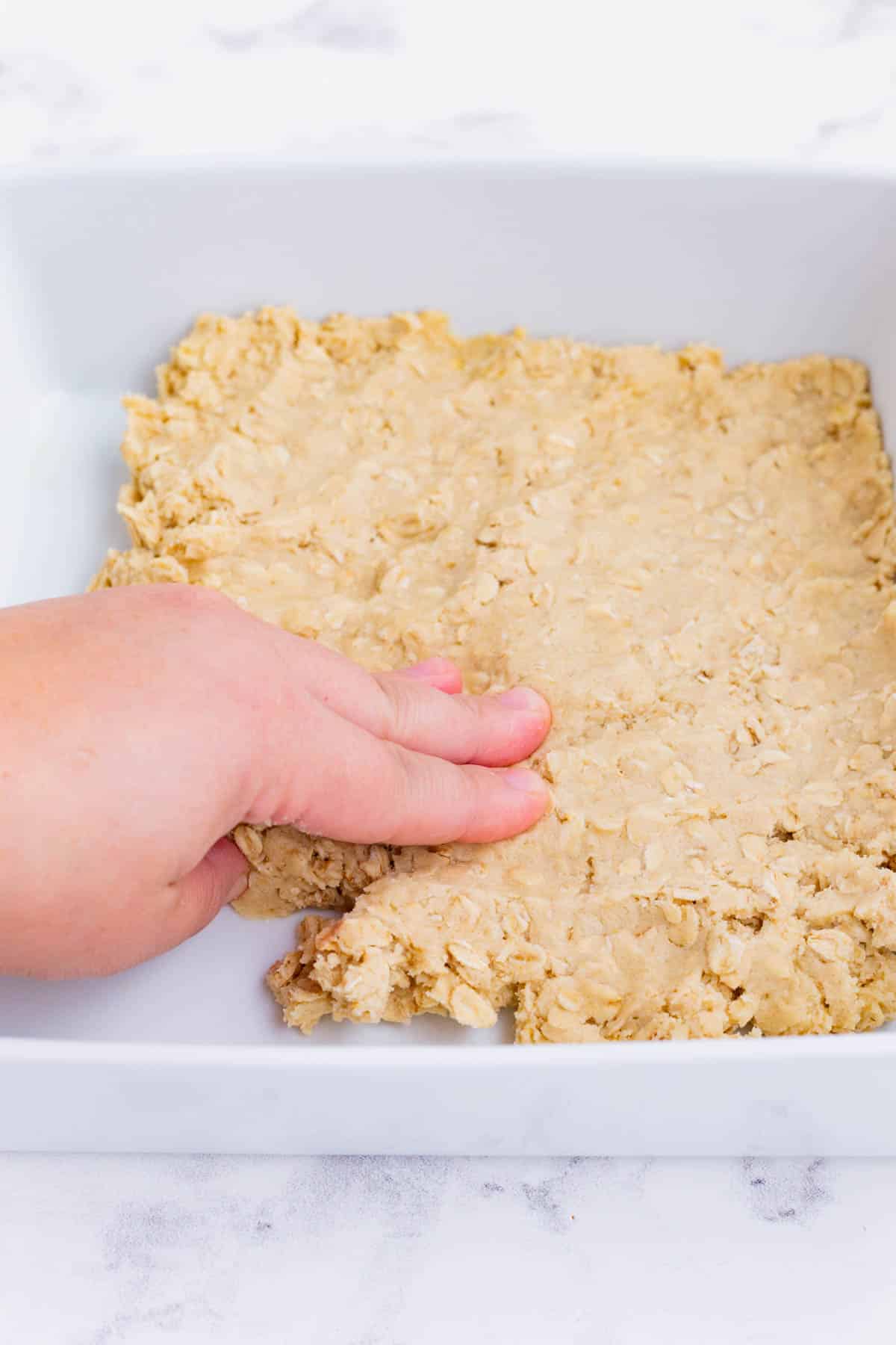 Shortbread dough is pressed into a baking dish.