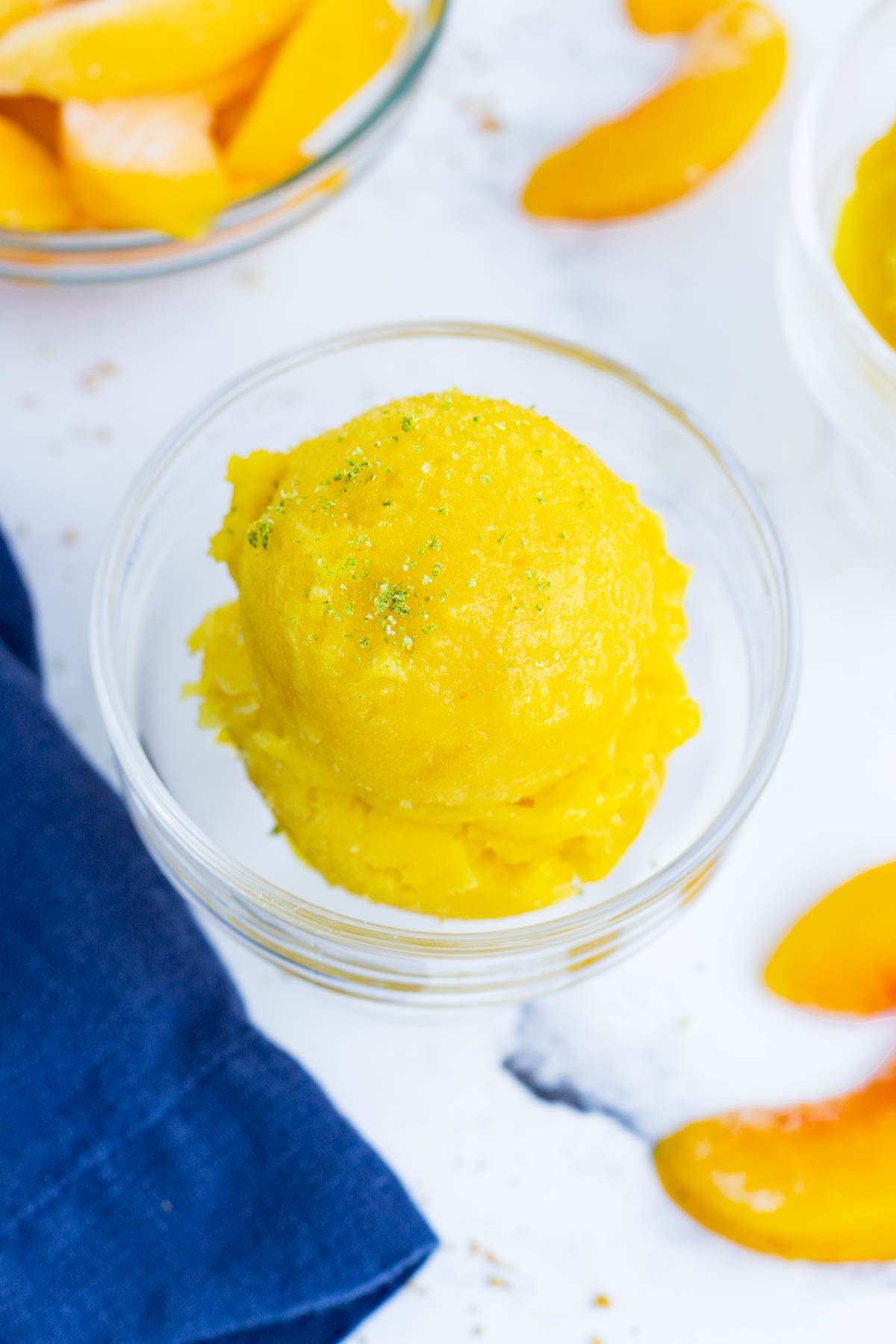 An overhead shot of peach sorbet surrounded by fresh peaches.