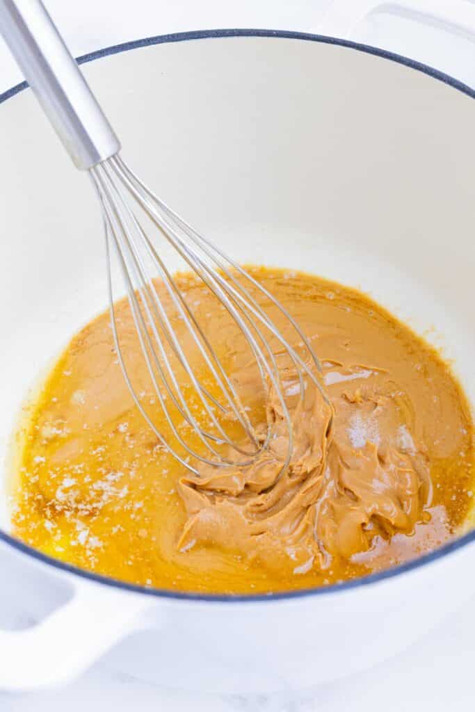 Melted butter and peanut butter are stirred together.