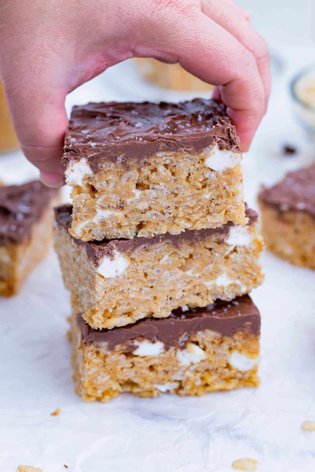 A hand picks up a peanut butter rice crispy treat.