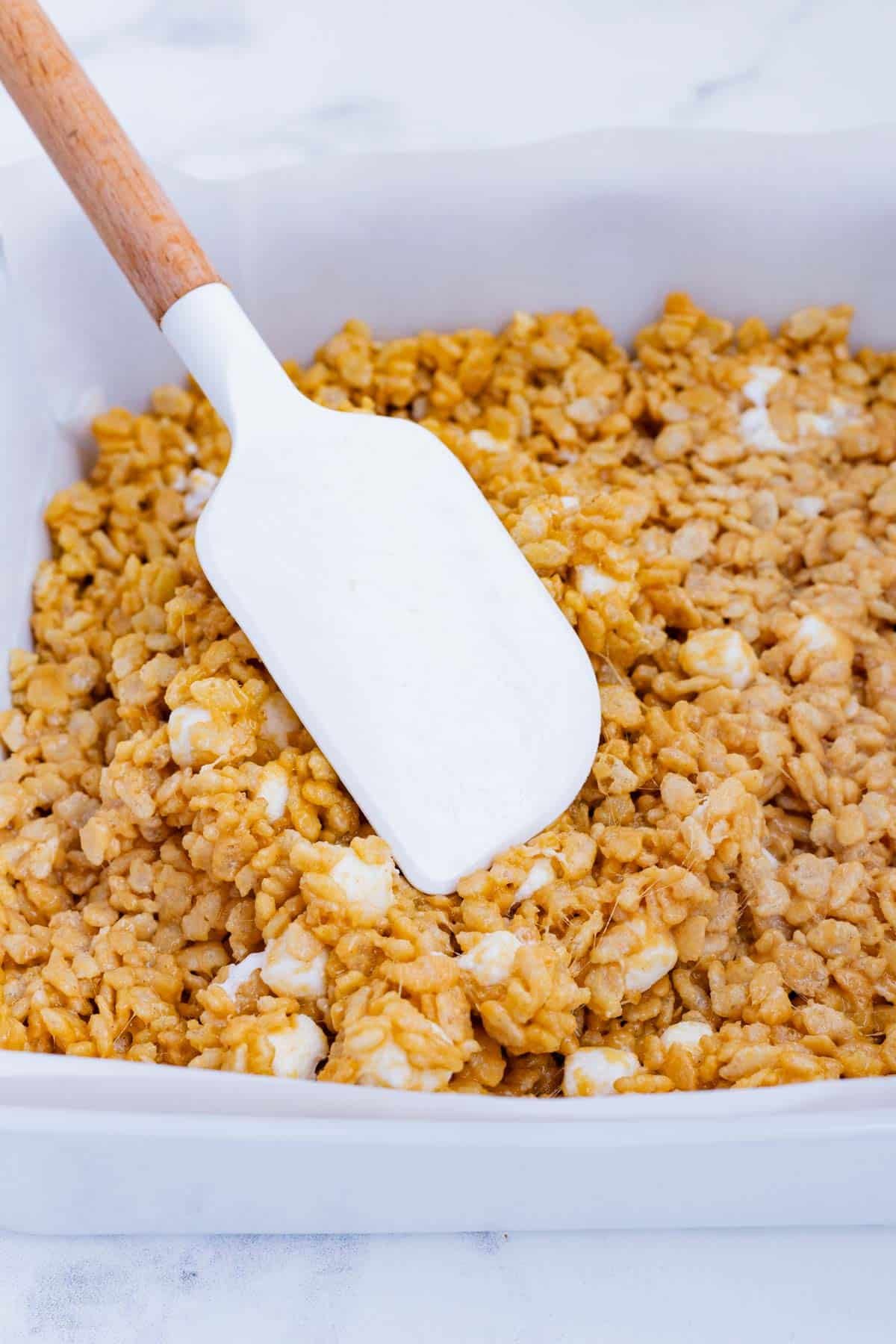 A spatula spreads the mixture out in a pan.