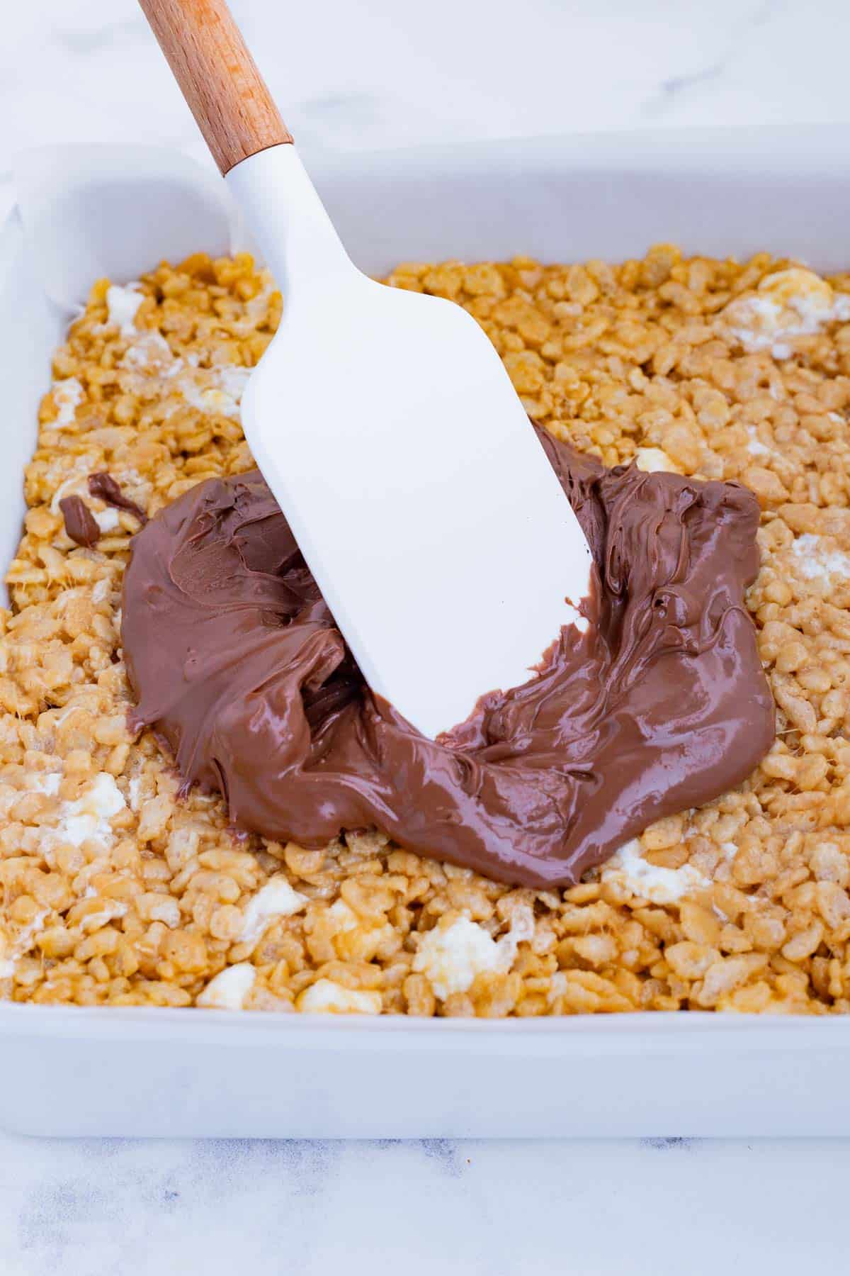 Melted chocolate is spread over the top of the treat.