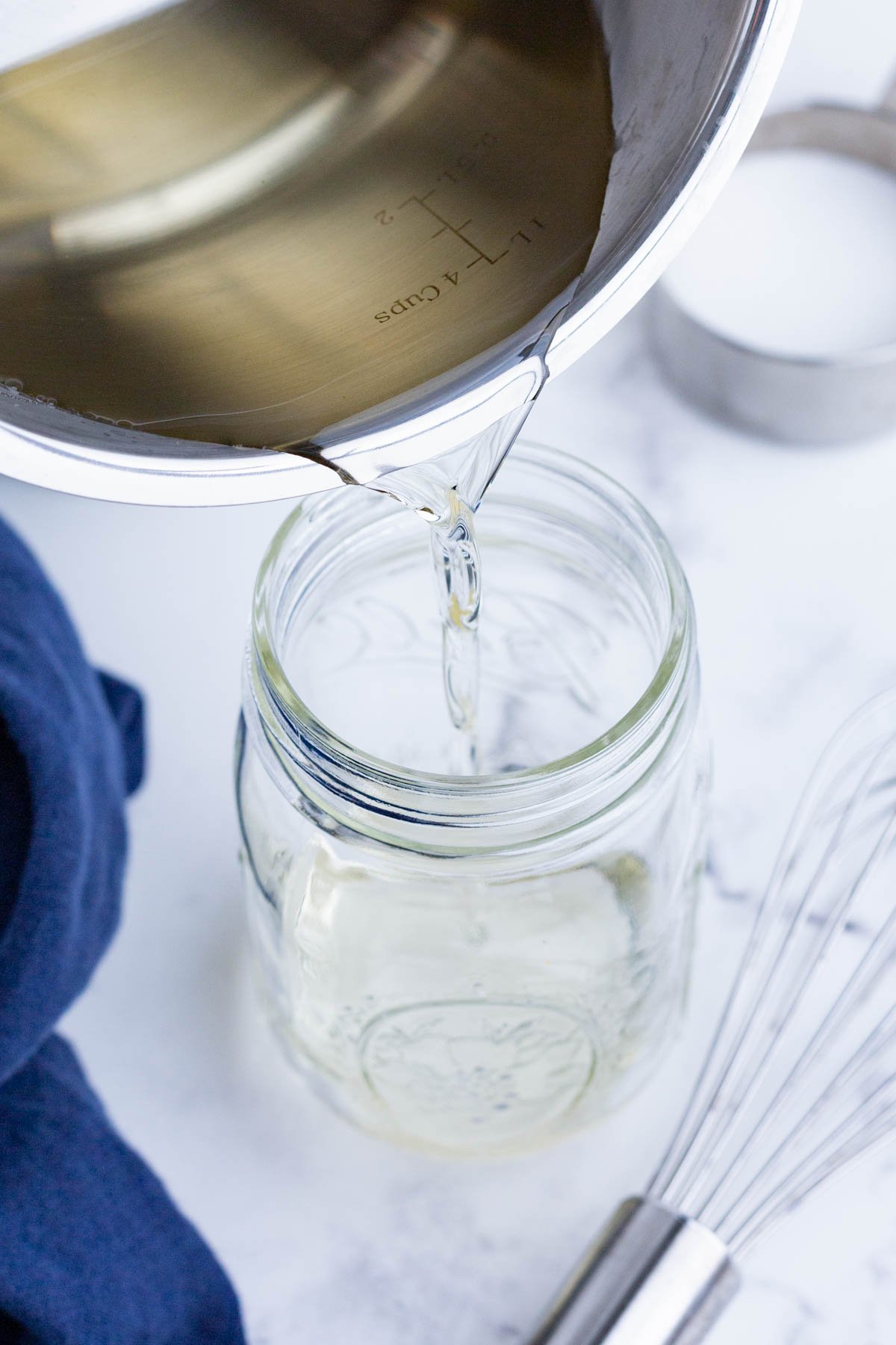 Cooled simple syrup is poured into a glass jar.
