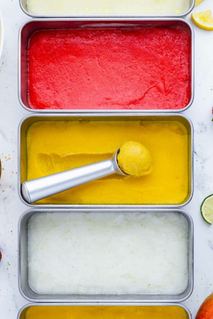 Different types of sorbet are frozen in loaf pans in the freezer.