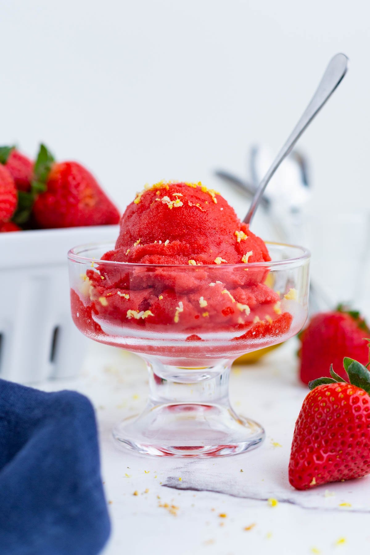 Two bowls of strawberry sorbet are surrounded by fresh fruit.