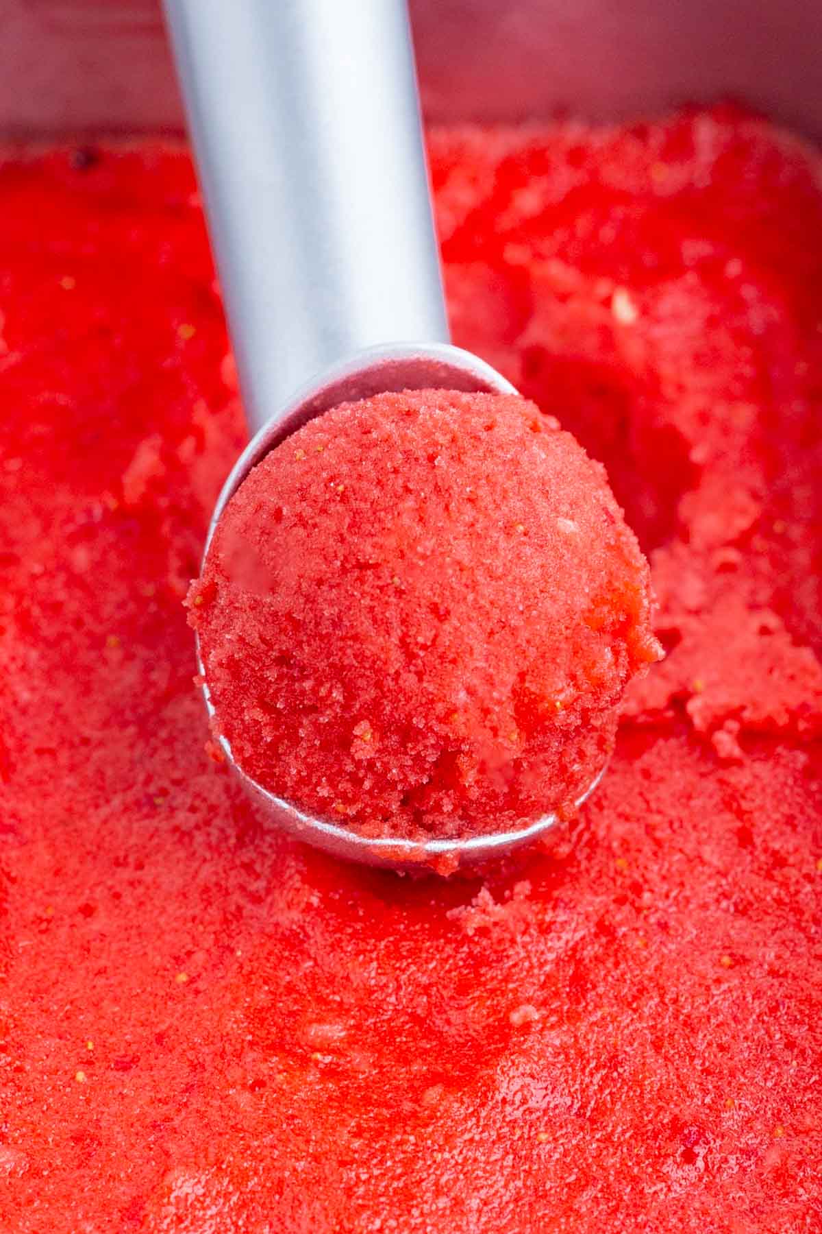 An ice cream scoop is used to serve strawberry sorbet.