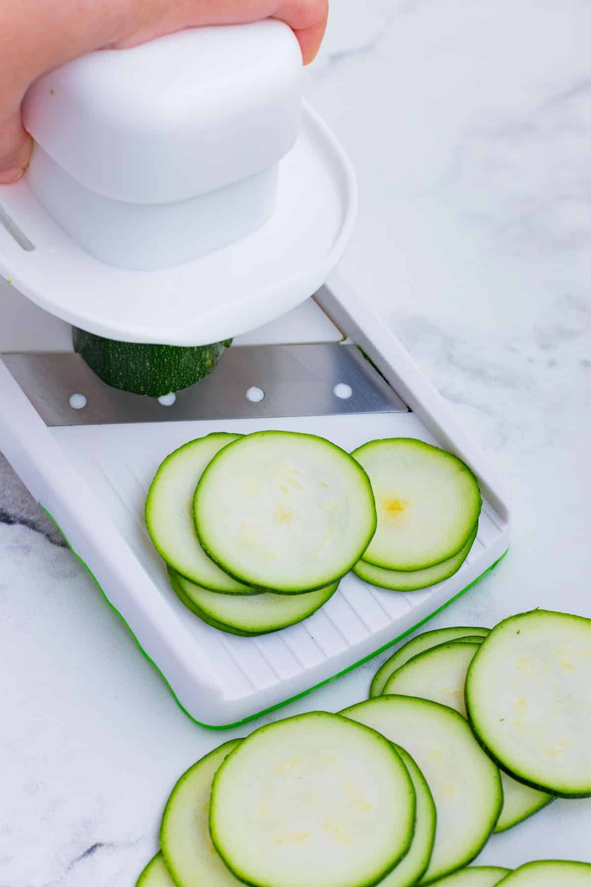 A mandolin is used to slice zucchini.