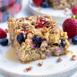 The baked oatmeal is served on a plate with fresh berries and syrup.