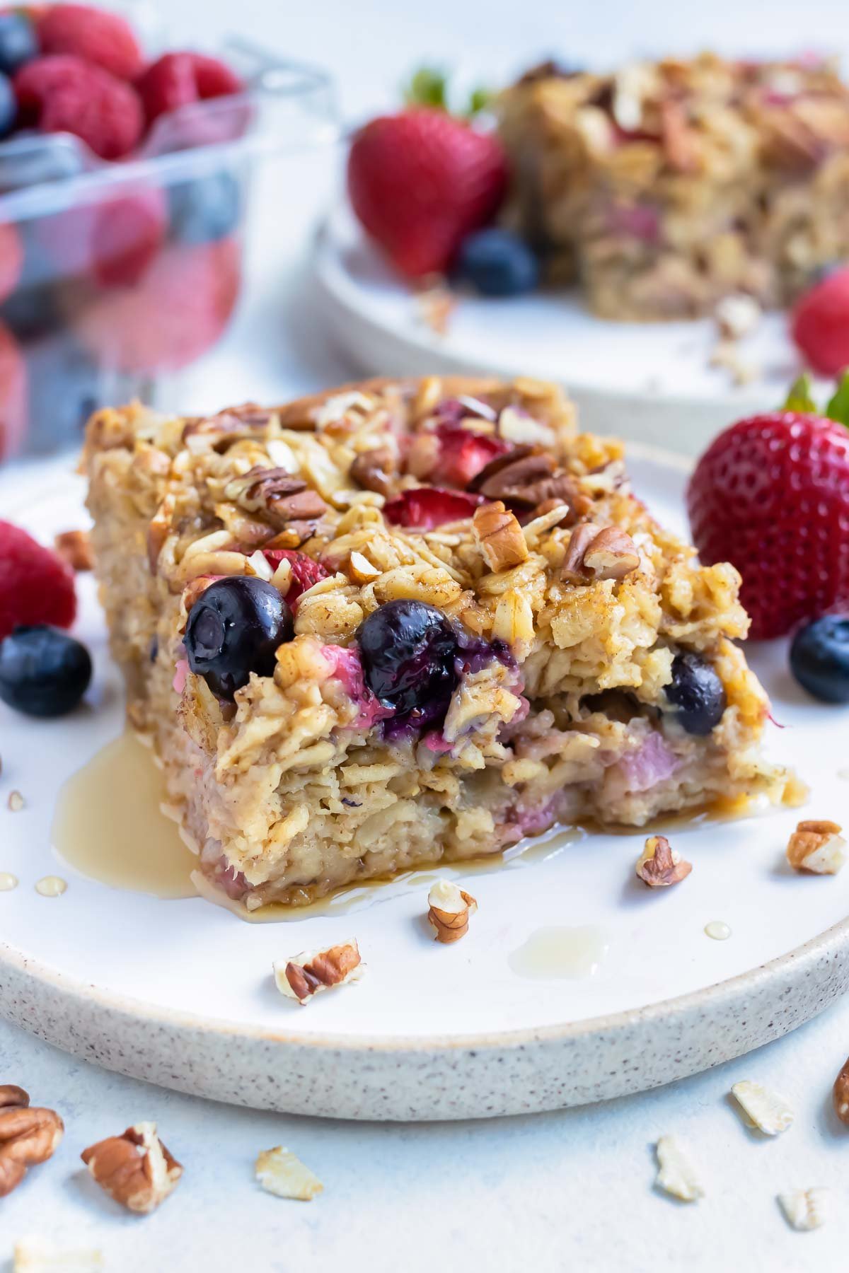 The baked oatmeal is served on a plate with fresh berries and syrup.