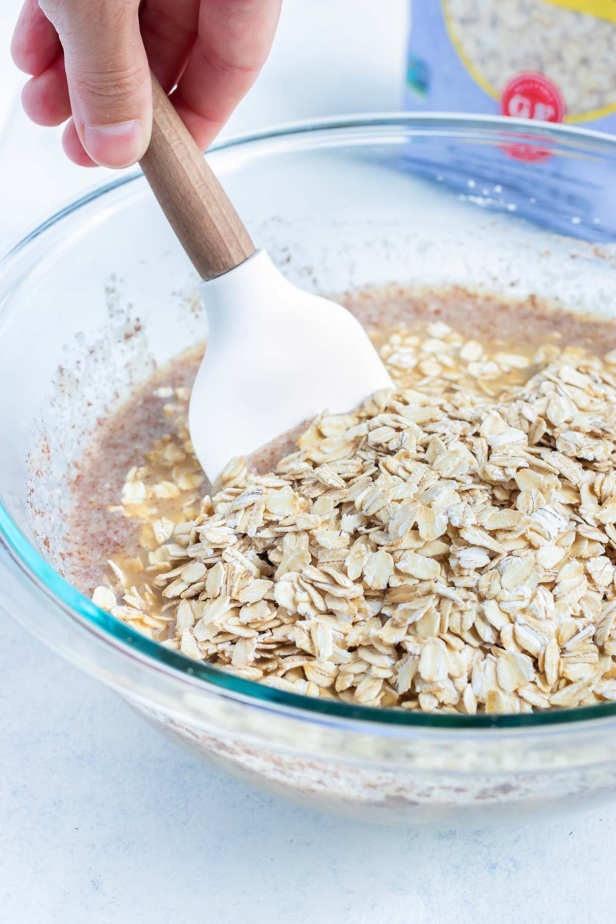The oats are mixed into the mixture in a bowl.