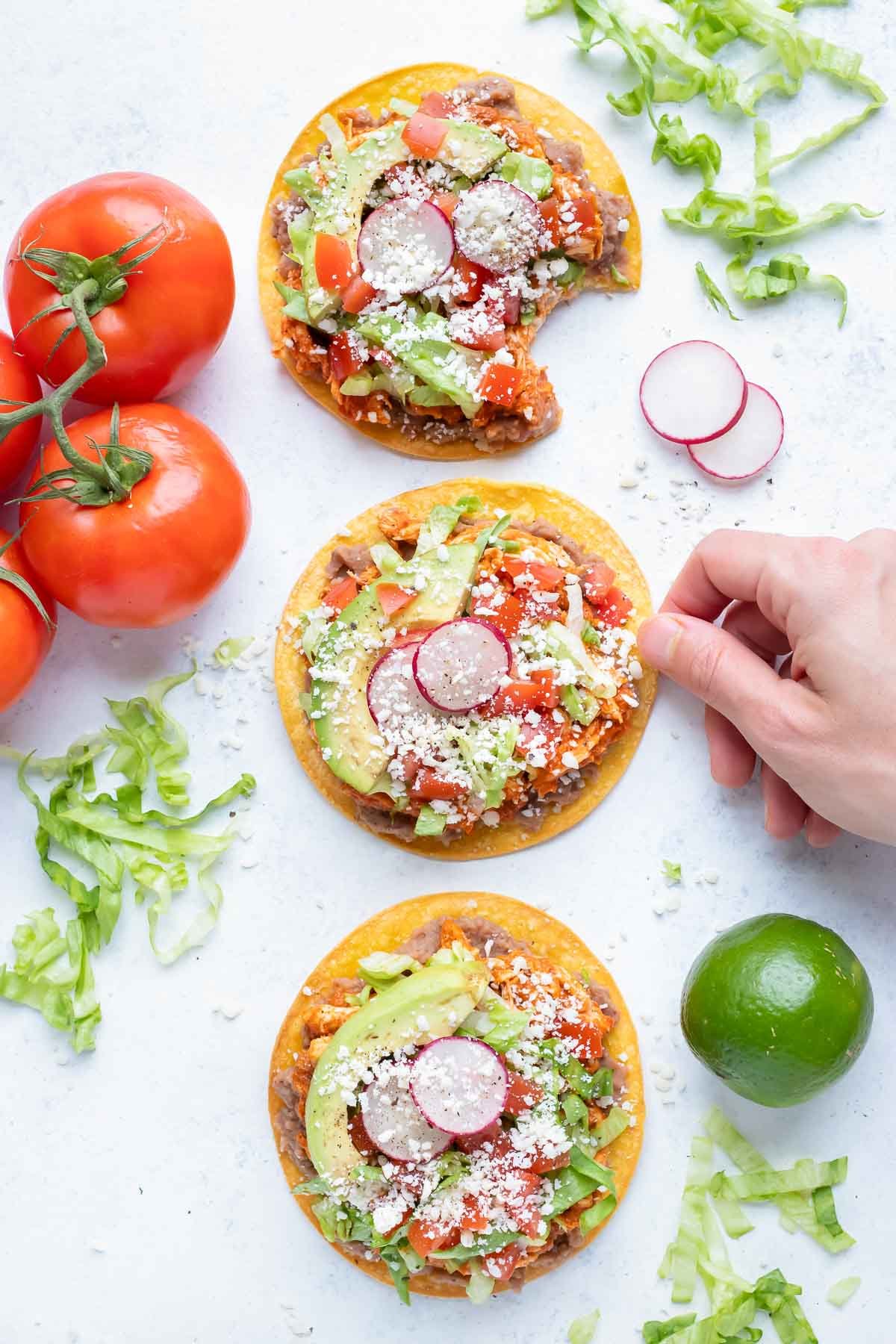 Three chicken tinga tostadas are served on the counter for a Mexican dinner dish.