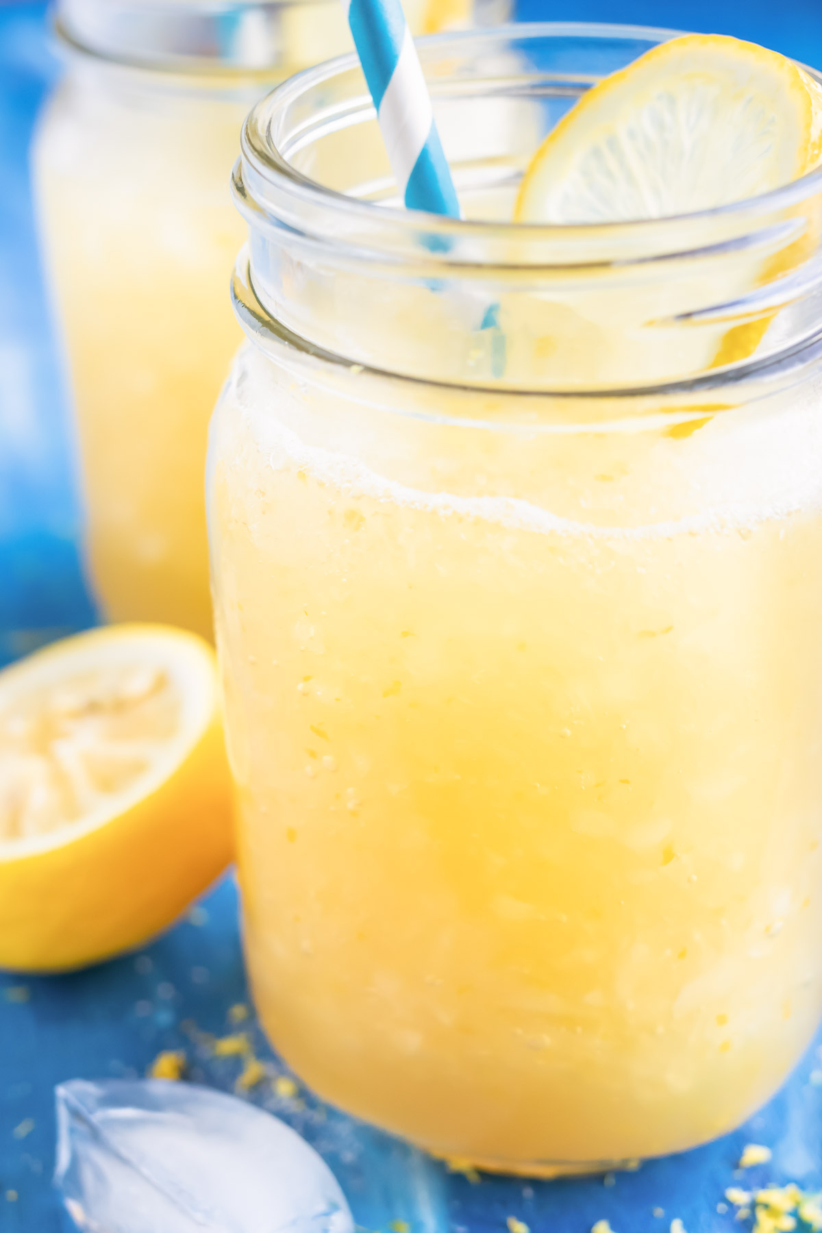 A glass full of a yellow icey drink made with lemons, sugar, and water.