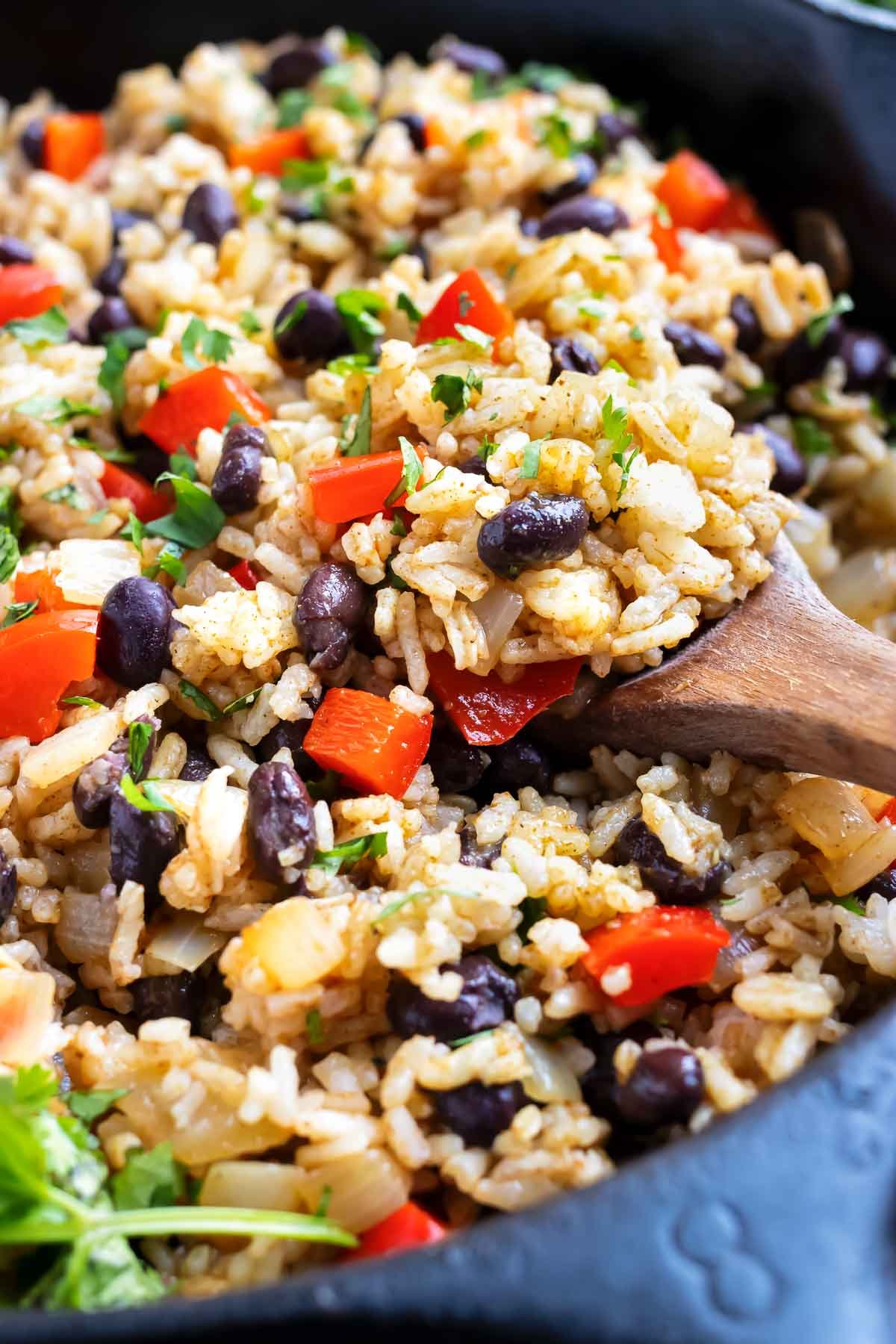 Black beans, rice, red bell peppers, and cilantro in a black skillet.