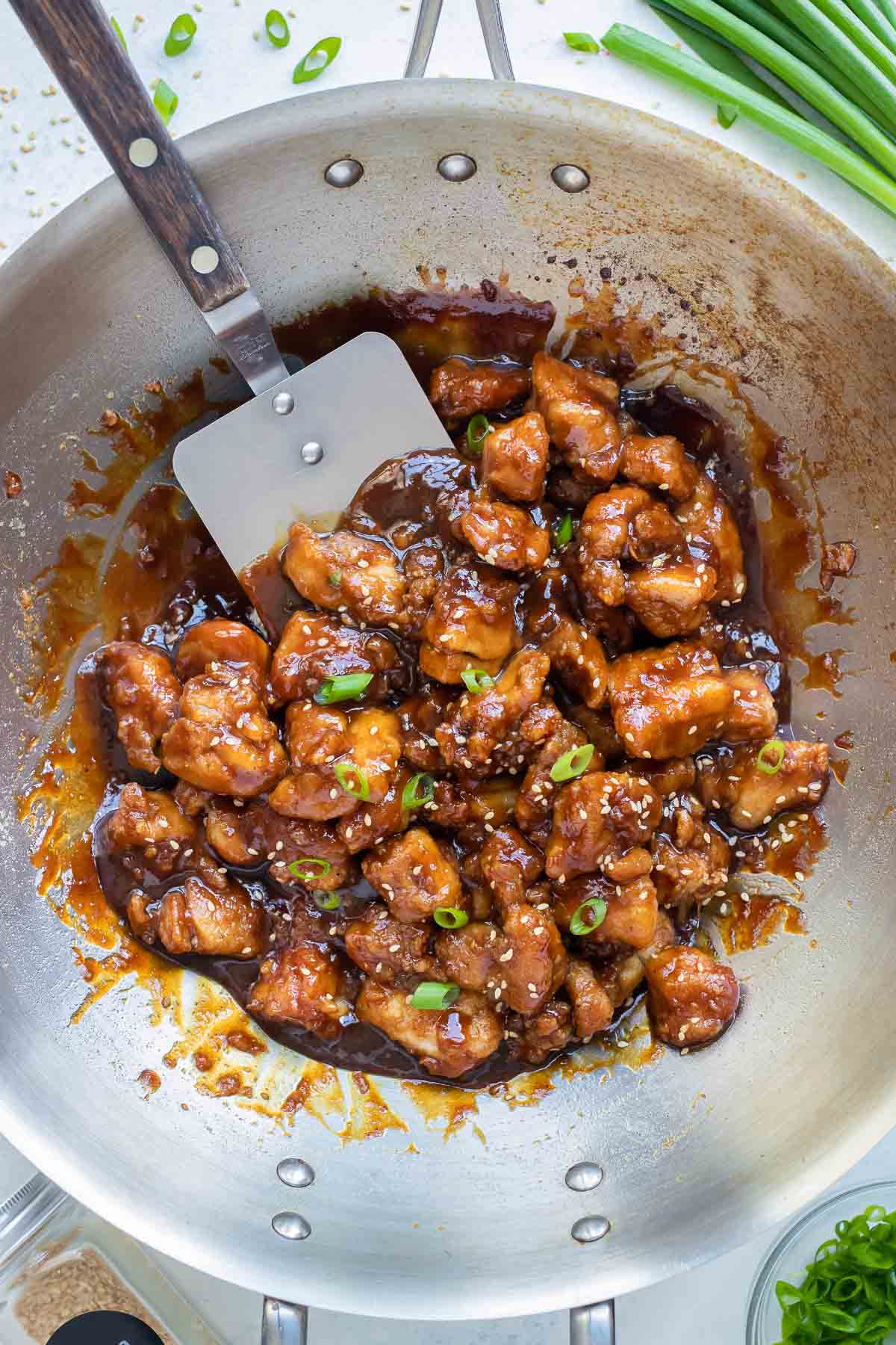 A spatula is scooping up a serving of crispy General Tso's chicken from a wok.