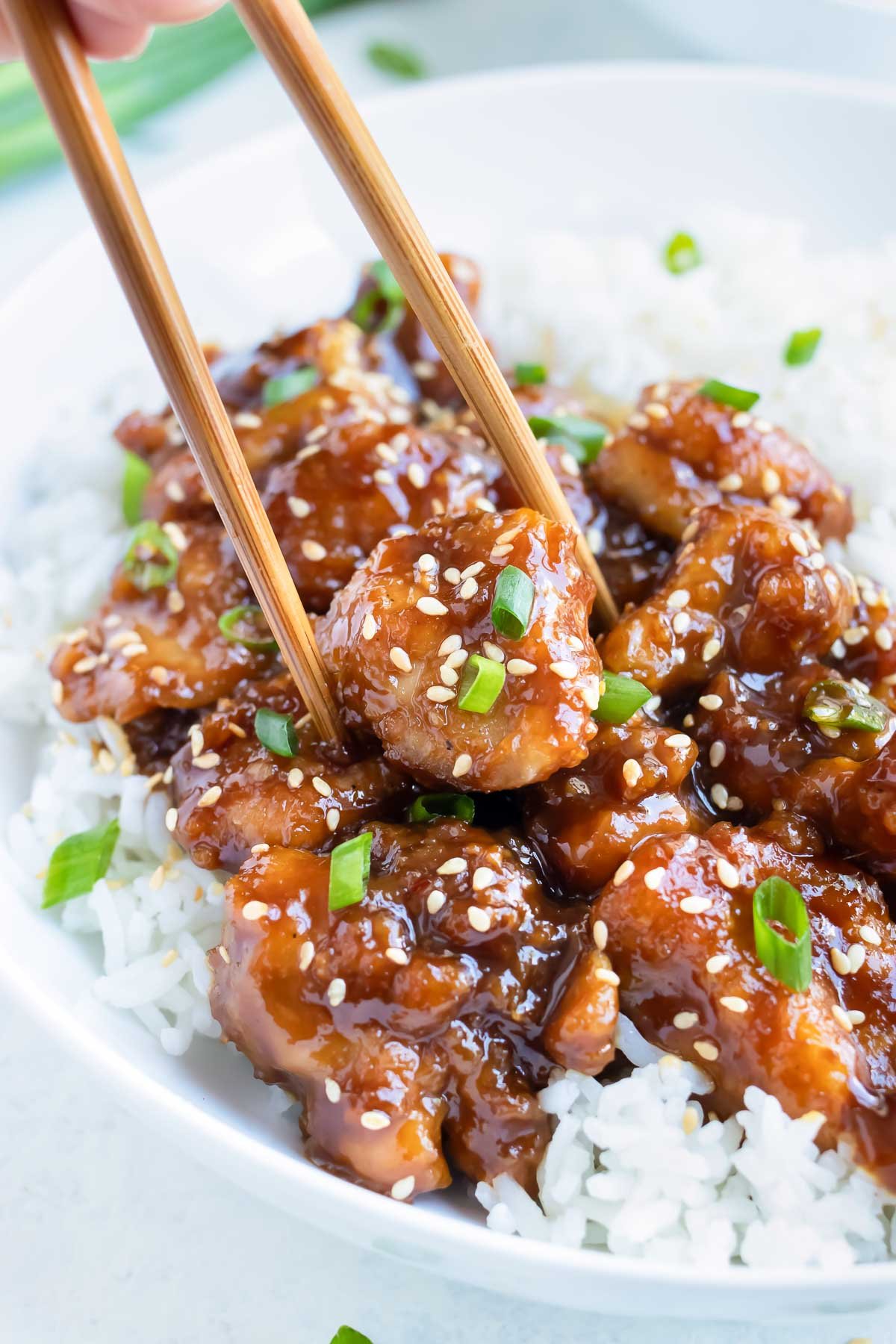 Chopsticks are used to lift up the sweet and sticky chicken.