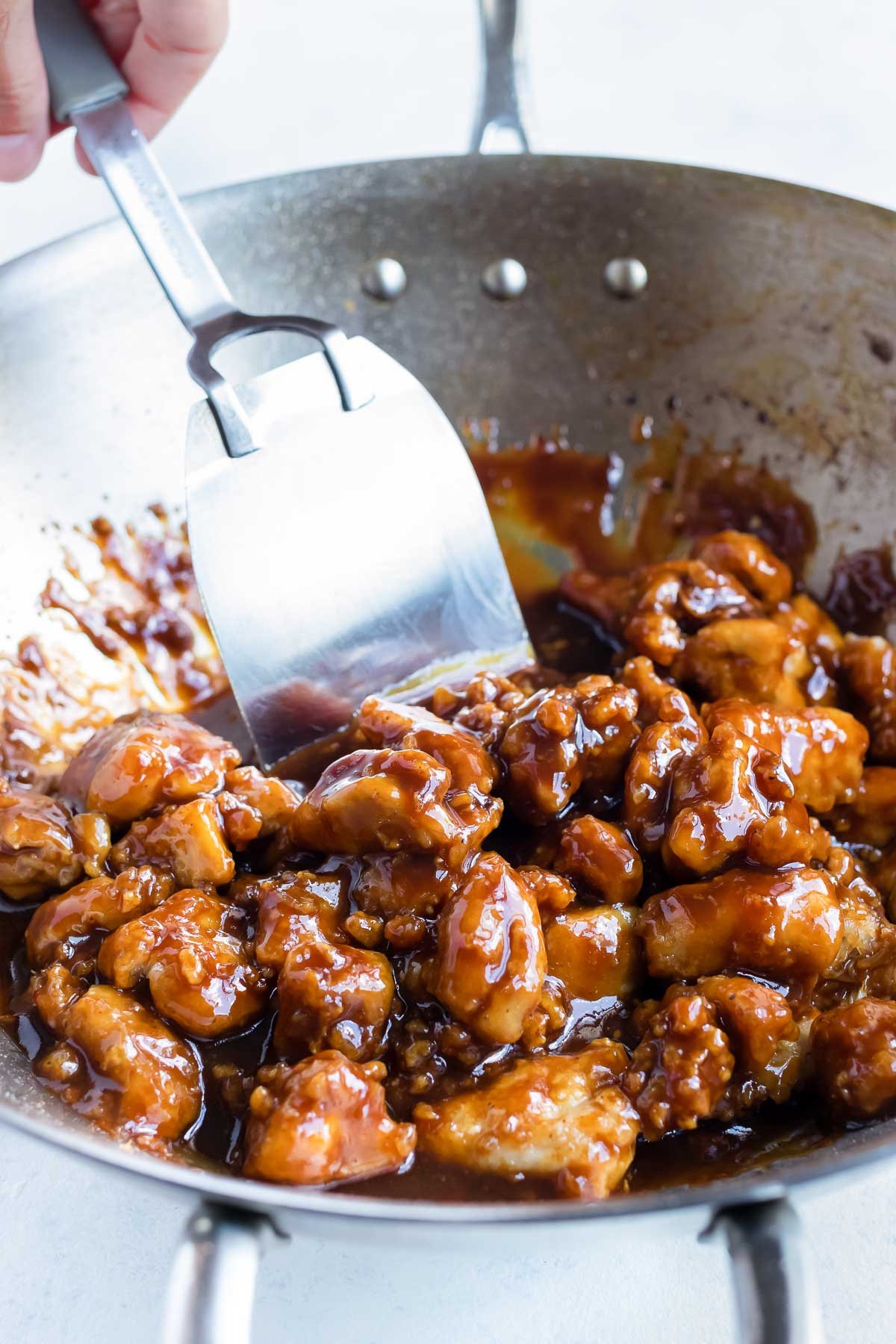 The homemade sauce is poured on the chicken in the skillet.