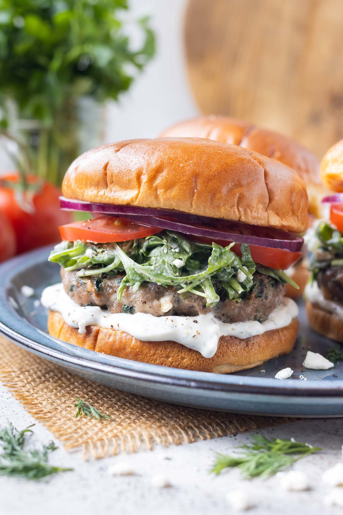 Greek turkey burgers with Mediterranean flavor are served on a blue plate for an easy summer dinner.