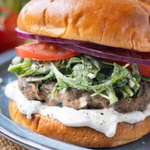 Greek turkey burgers with spinach and feta cheese are served with tzatziki sauce on a plate.