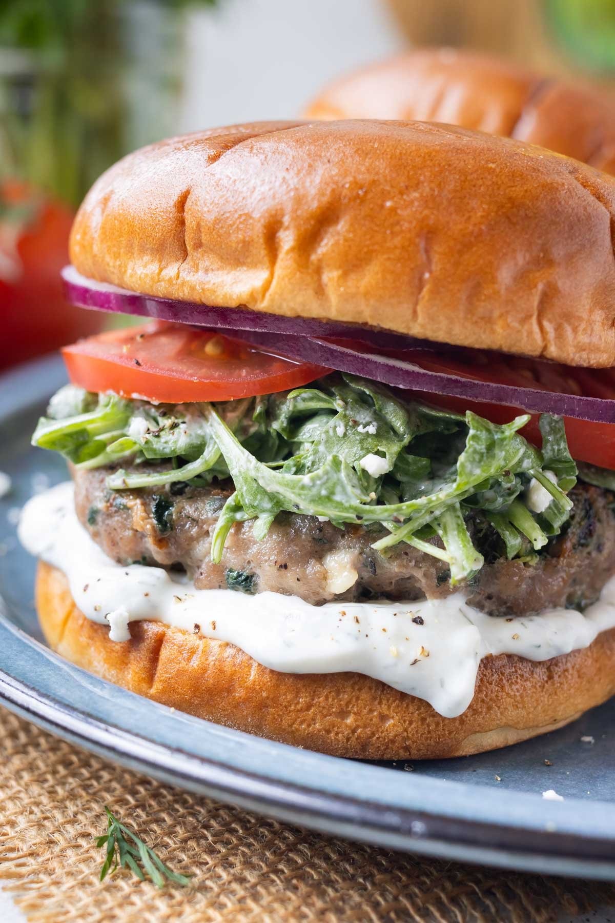 Greek turkey burgers with spinach and feta cheese are served with tzatziki sauce on a plate.
