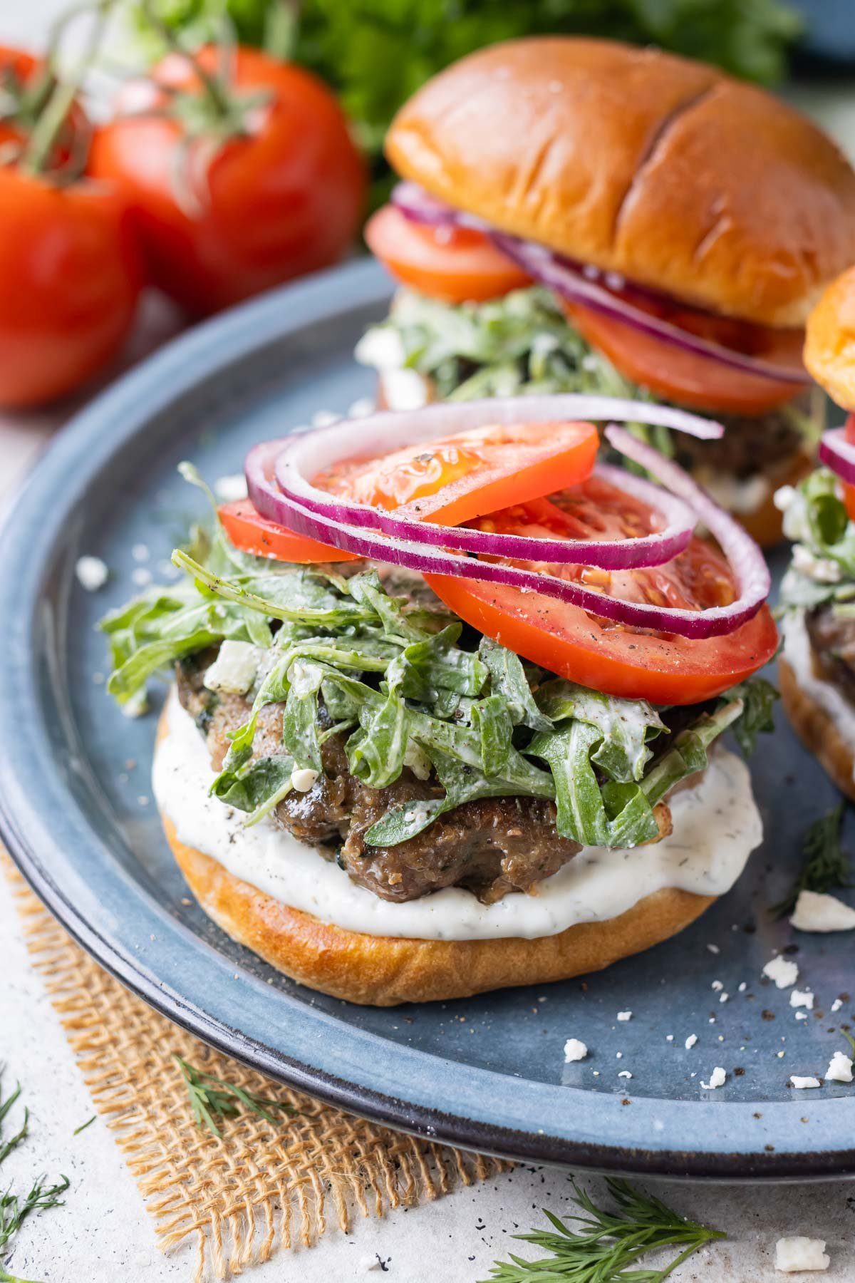 Top this Greek burger with tzatziki sauce, arugula slaw, and tomatoes.