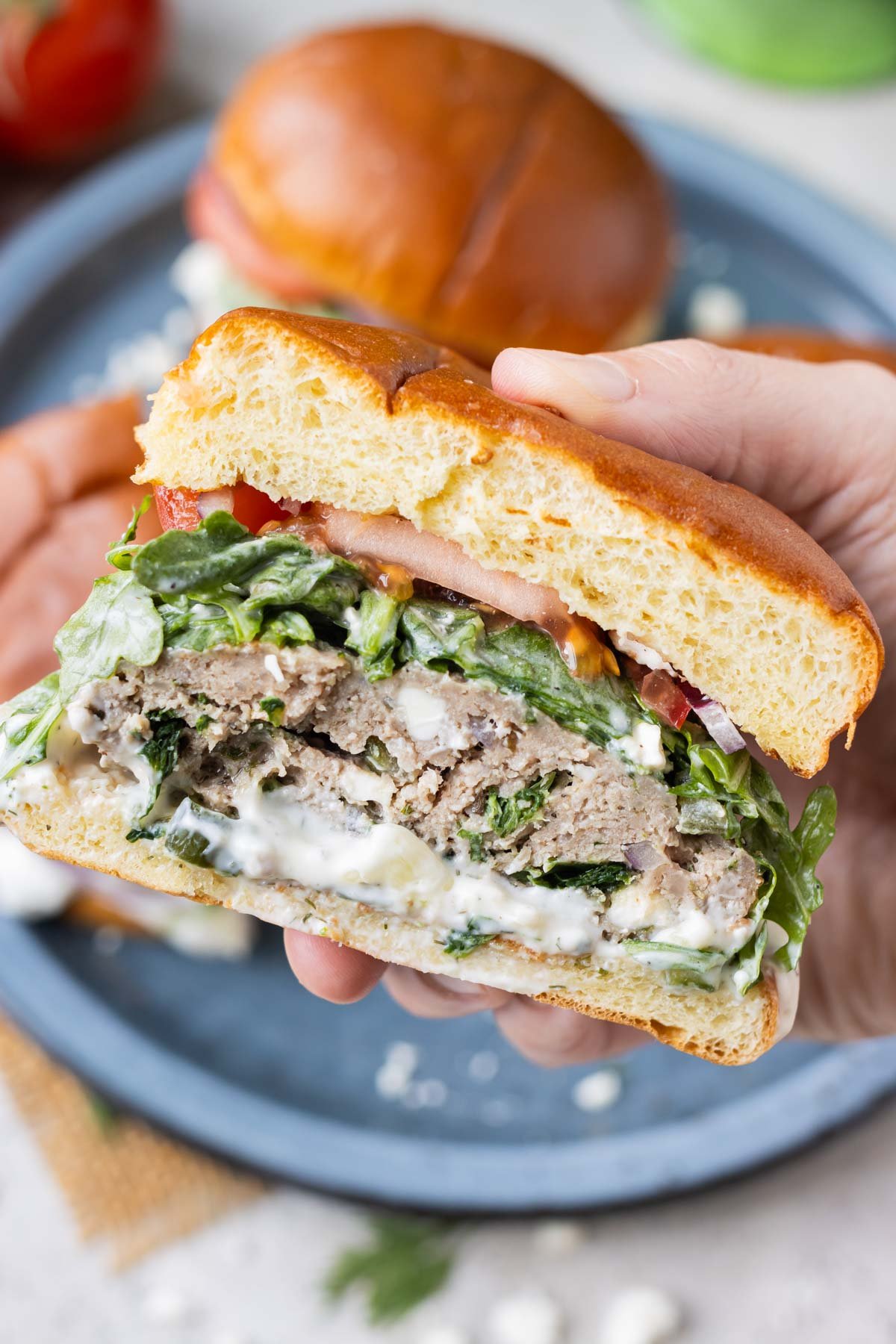 A Greek turkey burger is sliced in half to show the spinach, feta cheese, and tzatziki sauce.