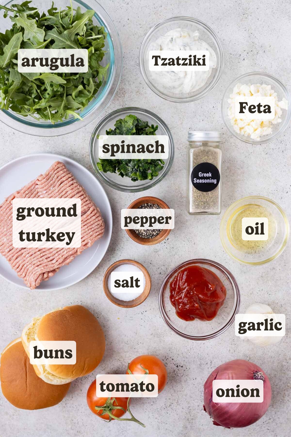 Ground turkey, arugula, Greek seasoning, onion, tomato, and buns are the main ingredients for this Greek turkey burger recipe.