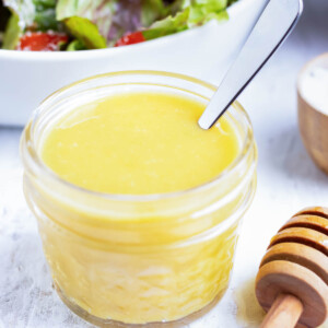 A clear container full of a healthy salad dressing made of honey and mustard.