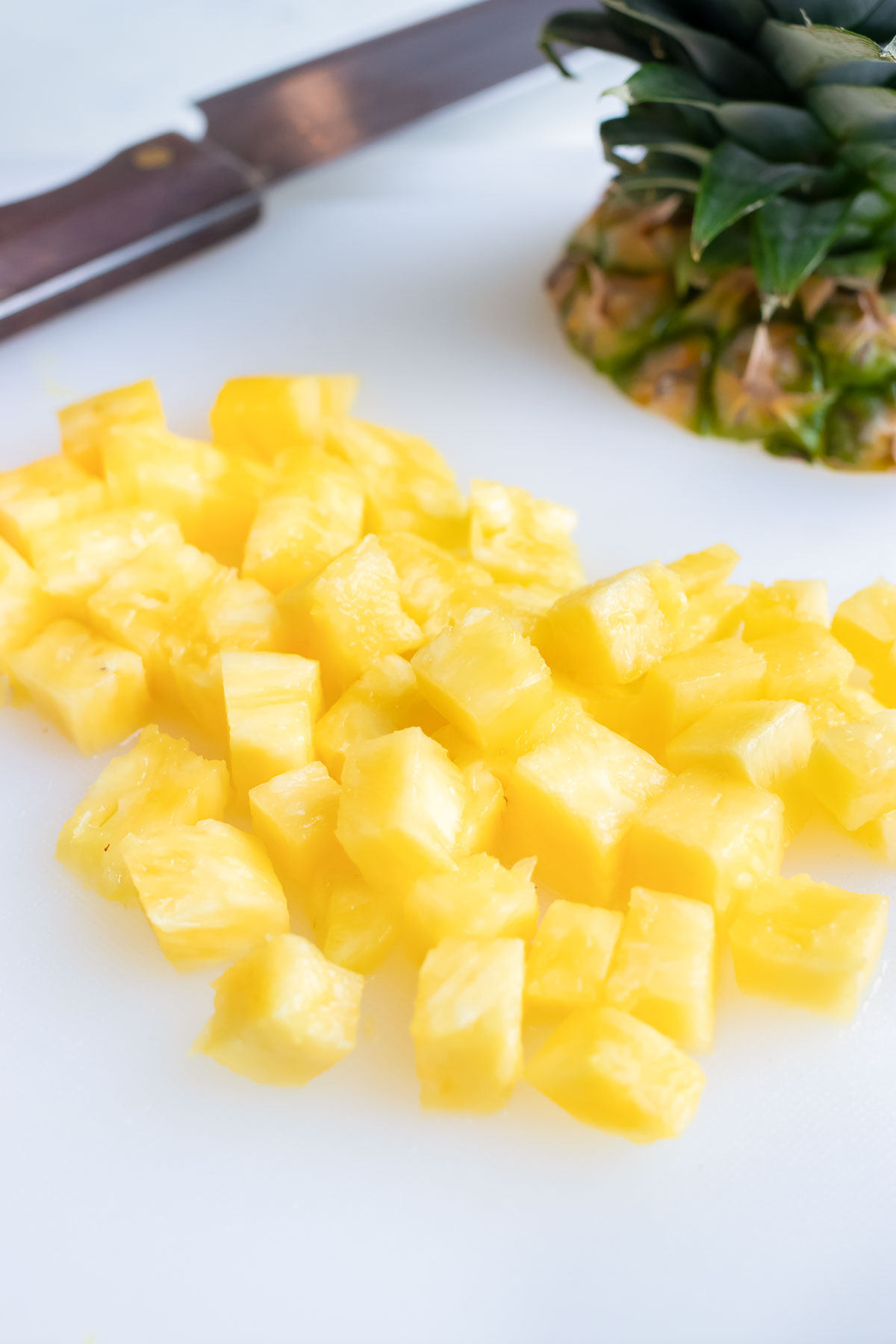 A pile of pineapple cubes are set on the counter.