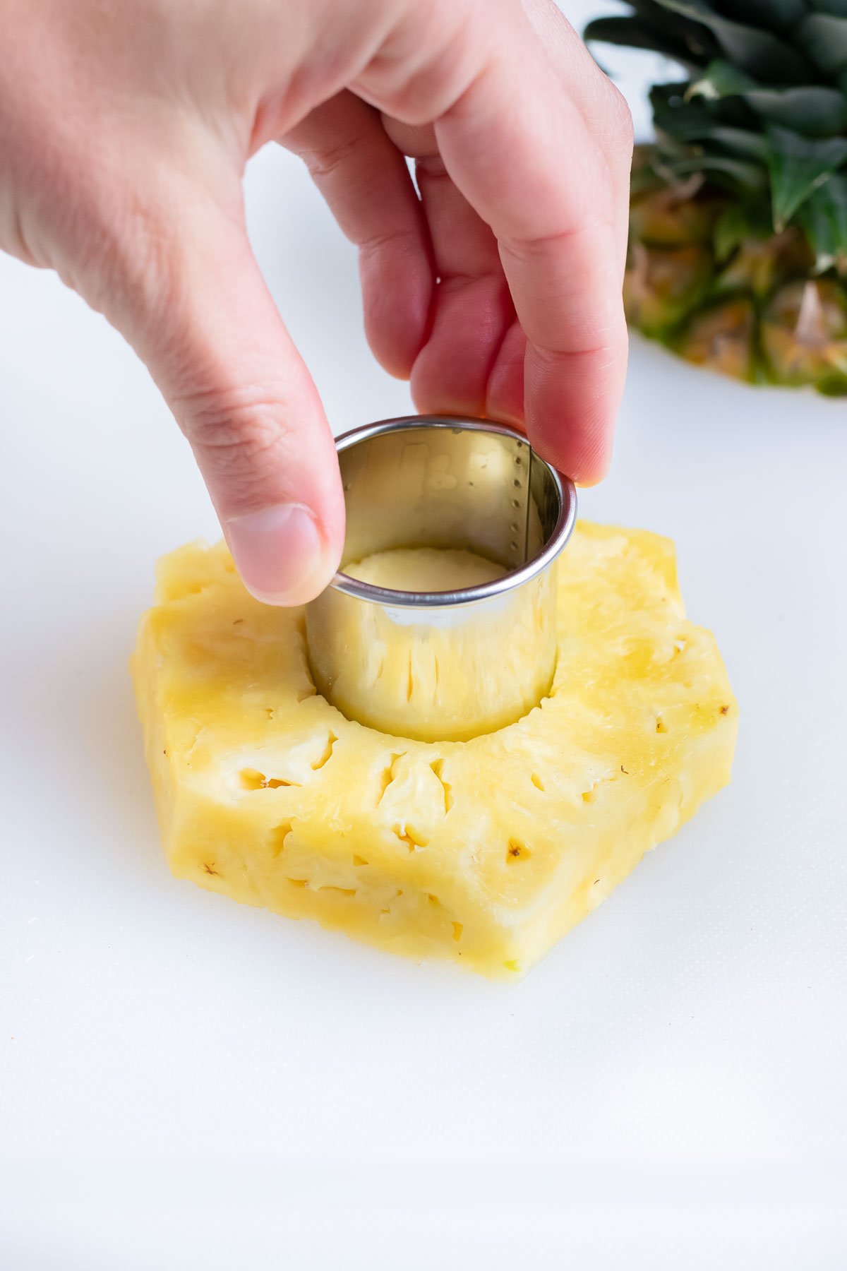 Removing the core from pineapple slices with a metal cookie cutter.