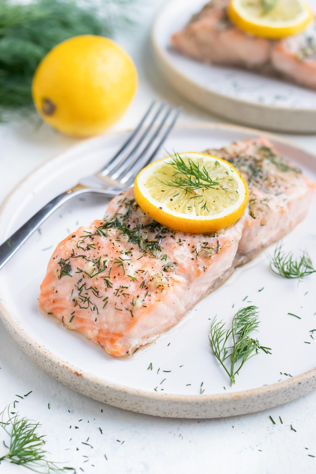 Lemon and dill salmon is served on a white plate with a fork.