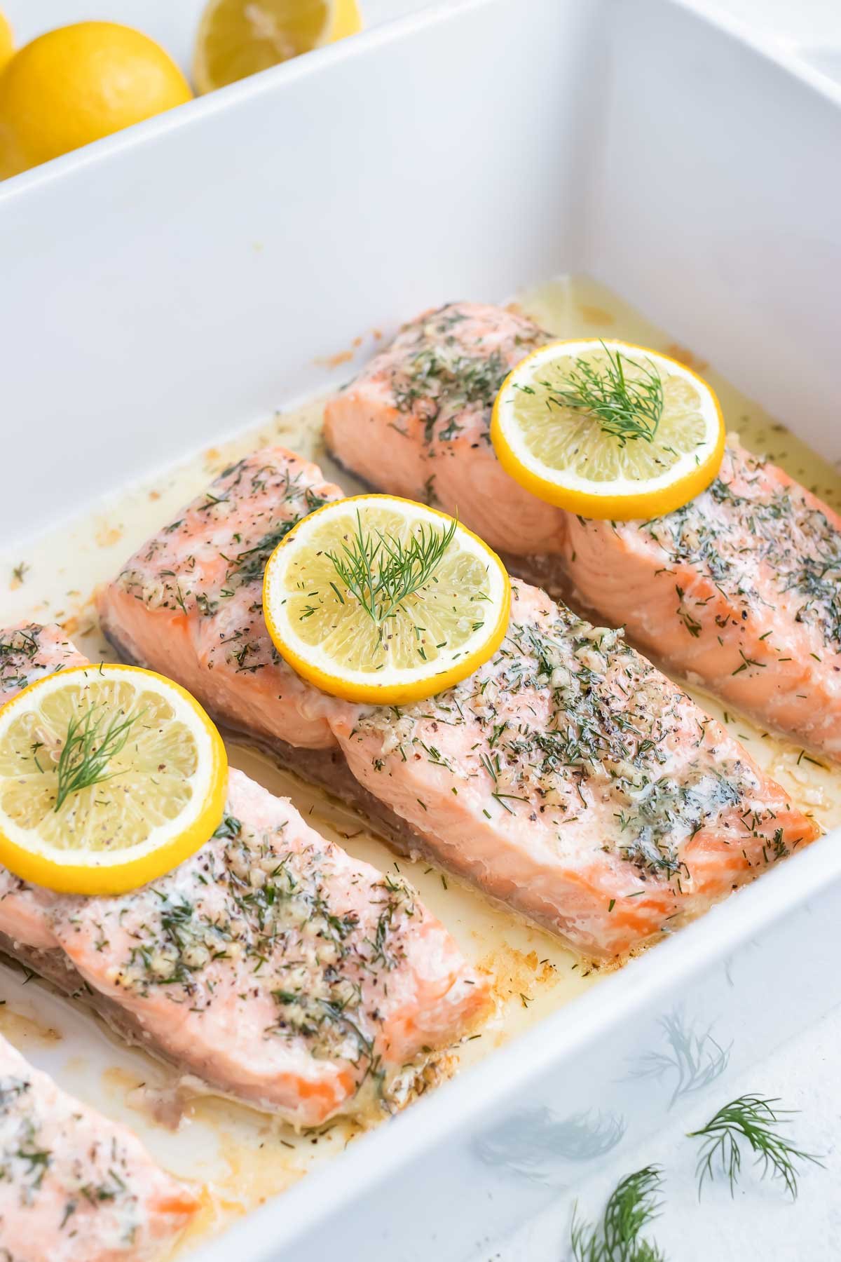 Lemon dill salmon is baked in the oven in a dish.