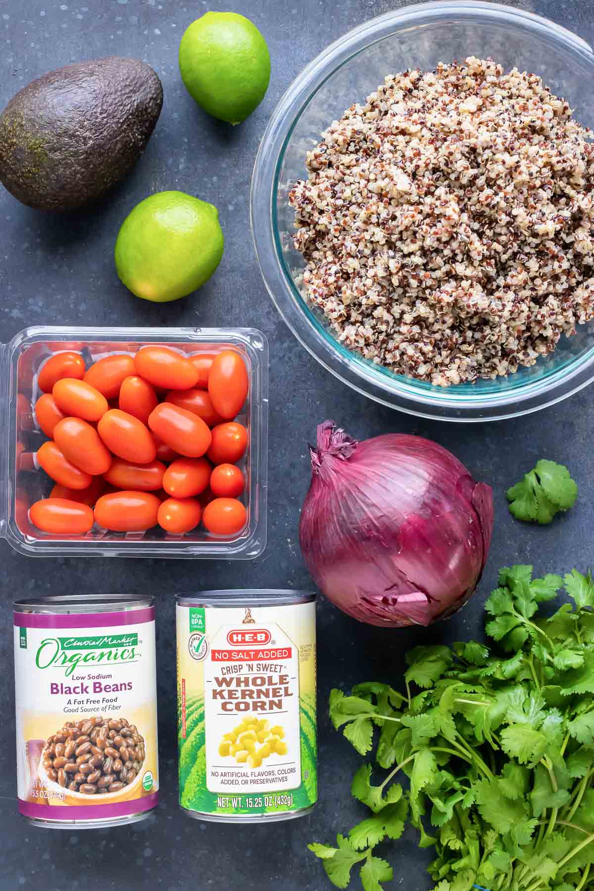 Cooked quinoa, avocado, tomatoes, beans, corn, and cilantro for a salad recipe.