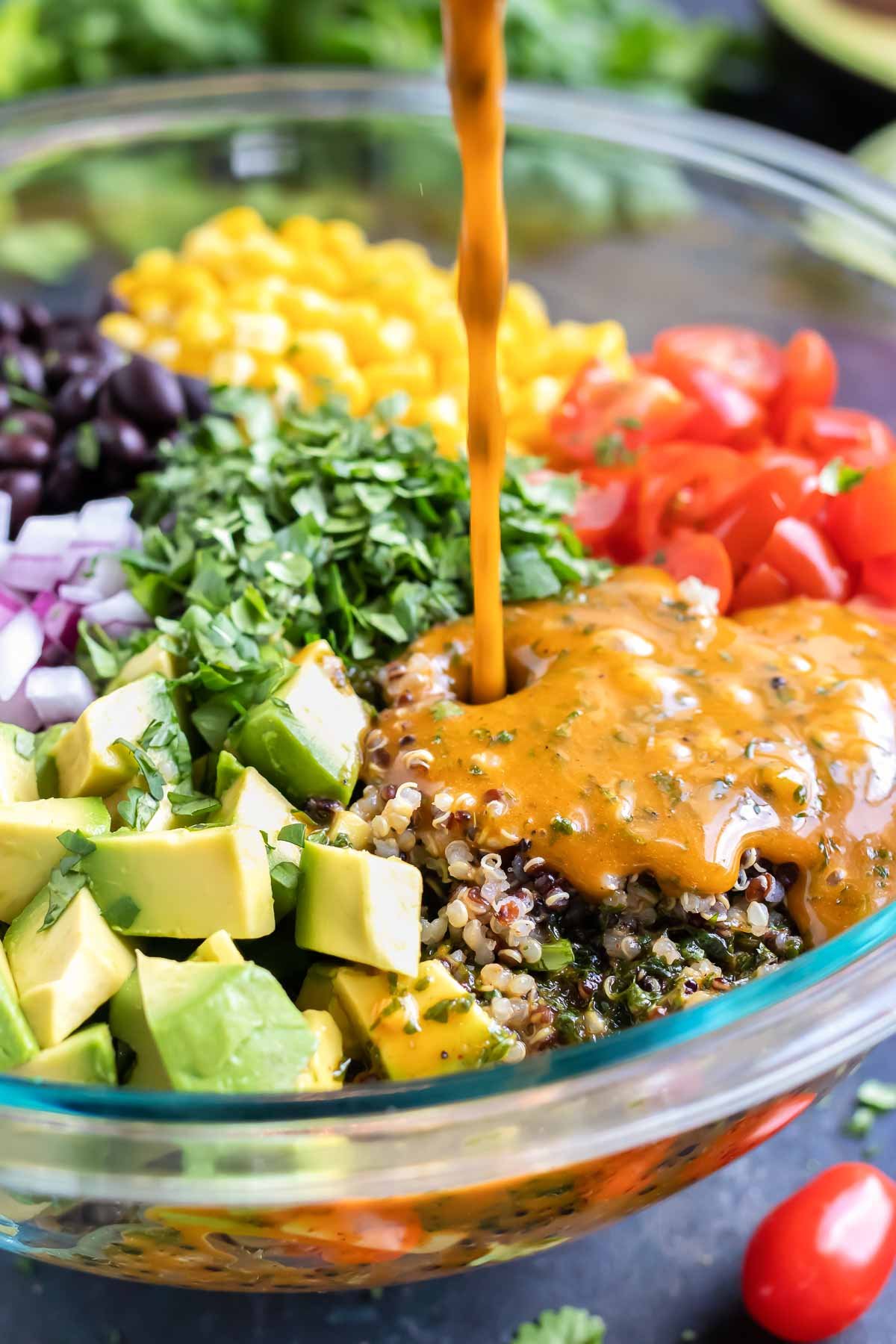 Homemade cilantro lime dressing being poured into a quinoa salad.