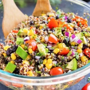 A Mexican Quinoa Salad with avocado in a clear glass bowl with a cilantro lime dressing.