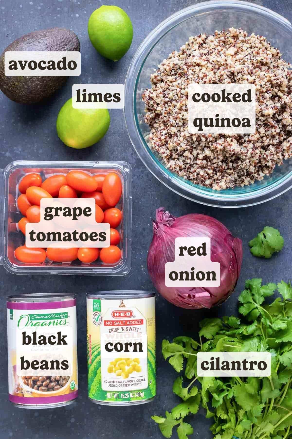 Quinoa, avocado, corn, black beans, cilantro and tomatoes are on a table as the ingredients for a Mexican Quinoa Salad.